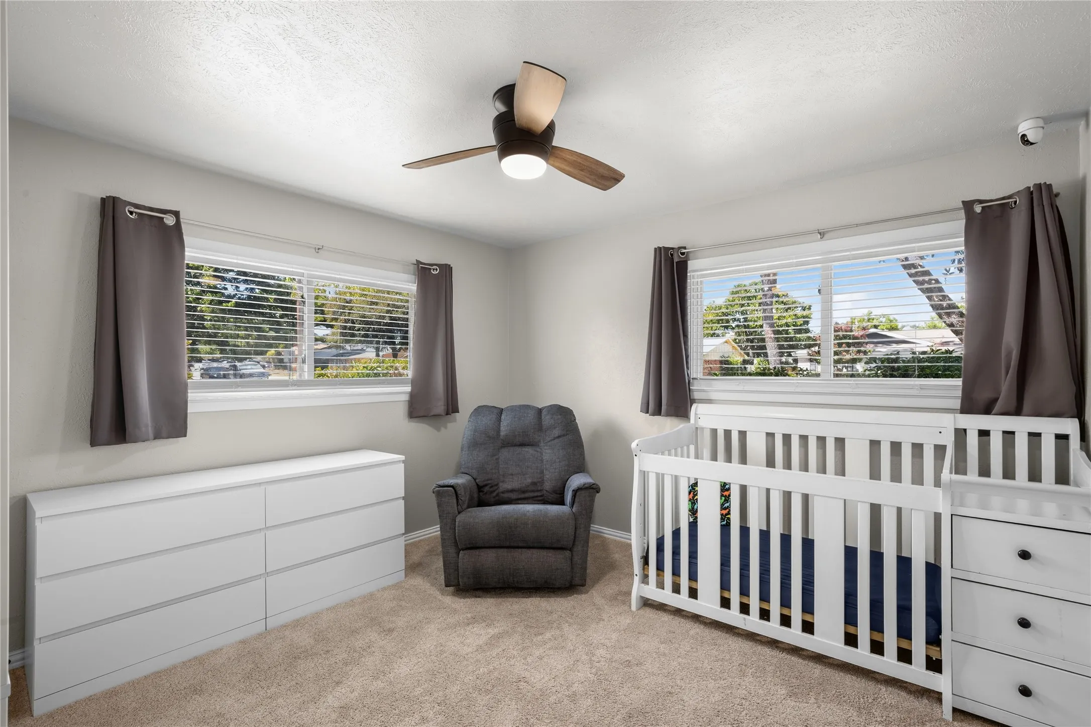 Carpeted room with a ceiling fan, two windows, and light-toned walls