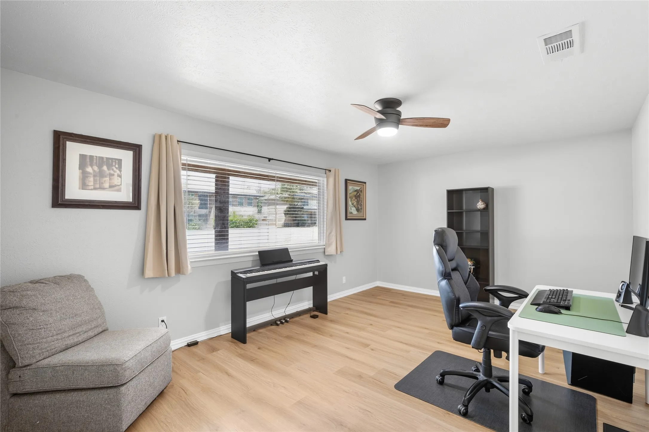 Wood-finish flooring, ceiling fan, and large window with blinds