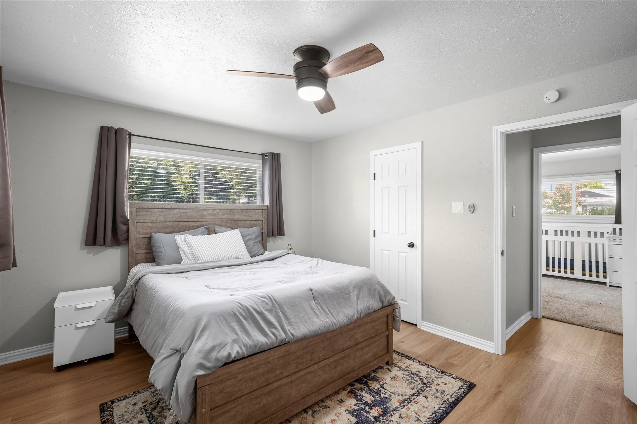 Wood-finish flooring, ceiling fan with integrated lighting, white paneled door, and neutral wall tones