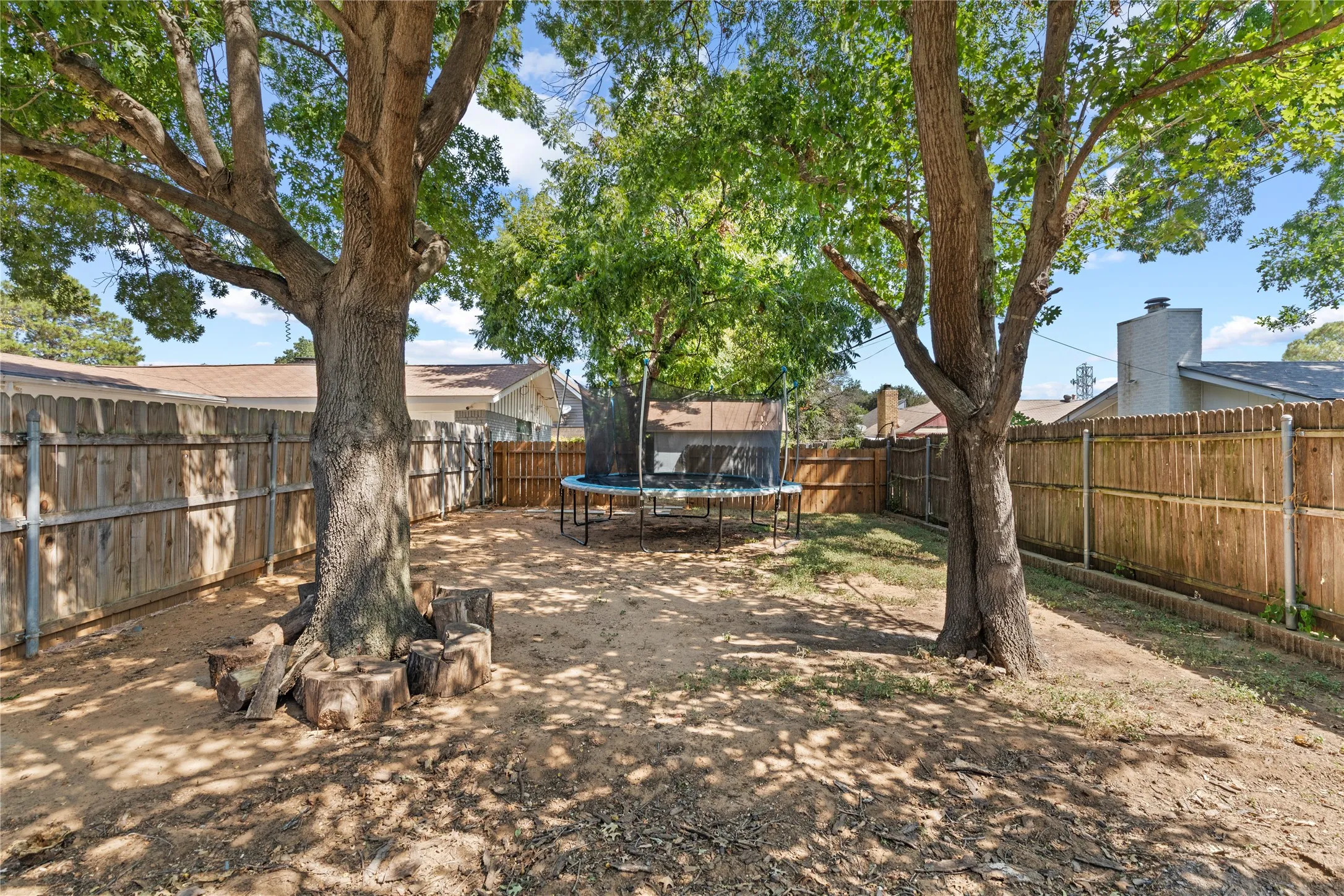 Fenced backyard featuring mature shade trees