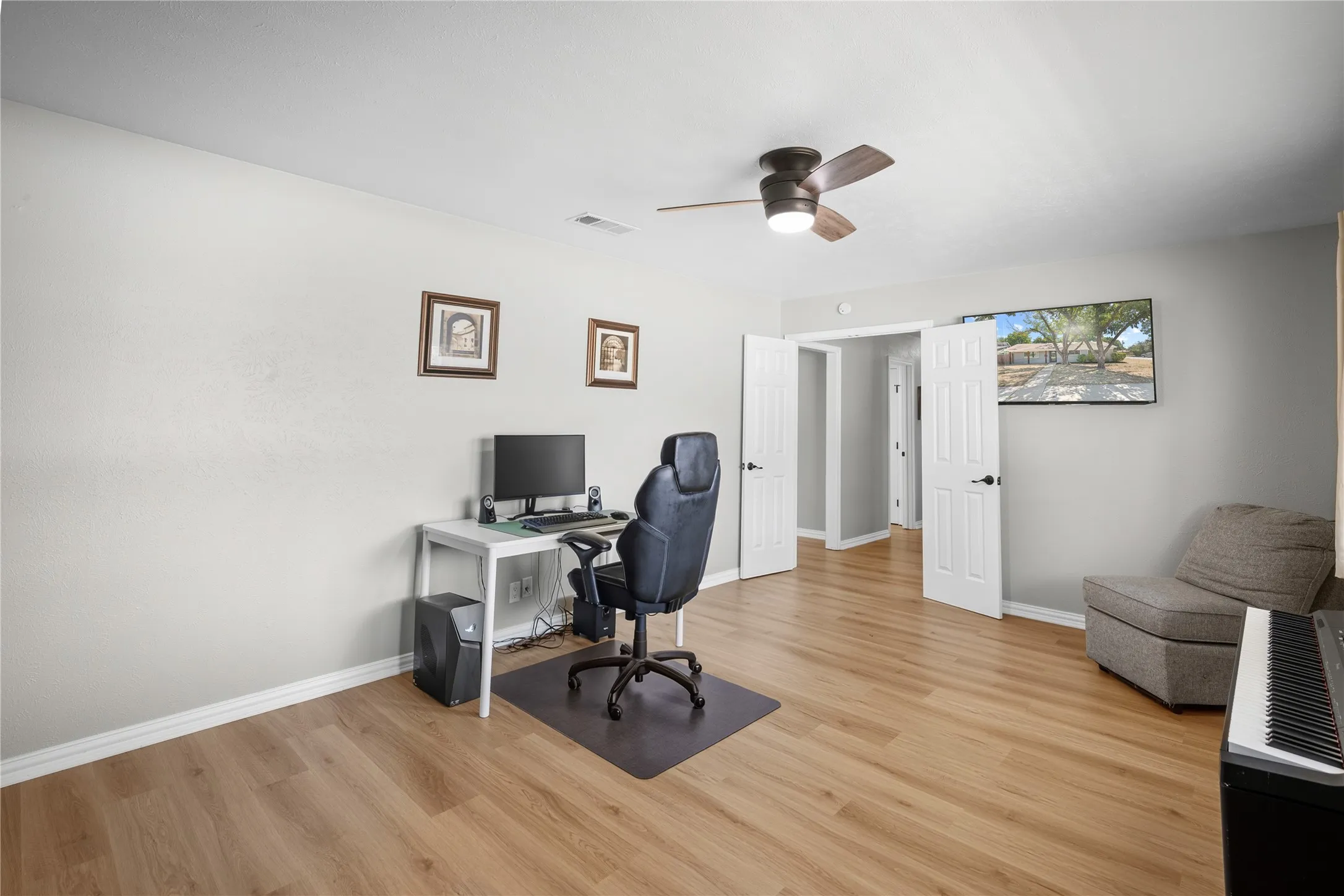 Wood-finish flooring throughout, light gray walls, white trim, and a ceiling fan with integrated lighting
