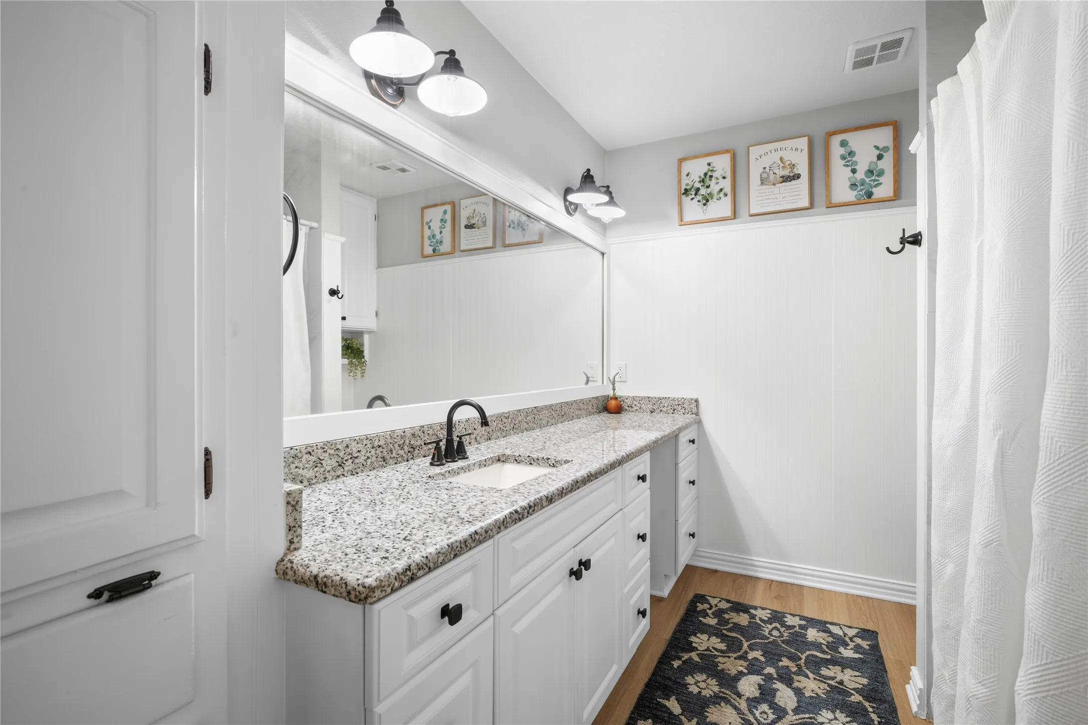 White cabinetry with dark hardware, a speckled countertop, and a built-in sink basin with a dark-finish faucet