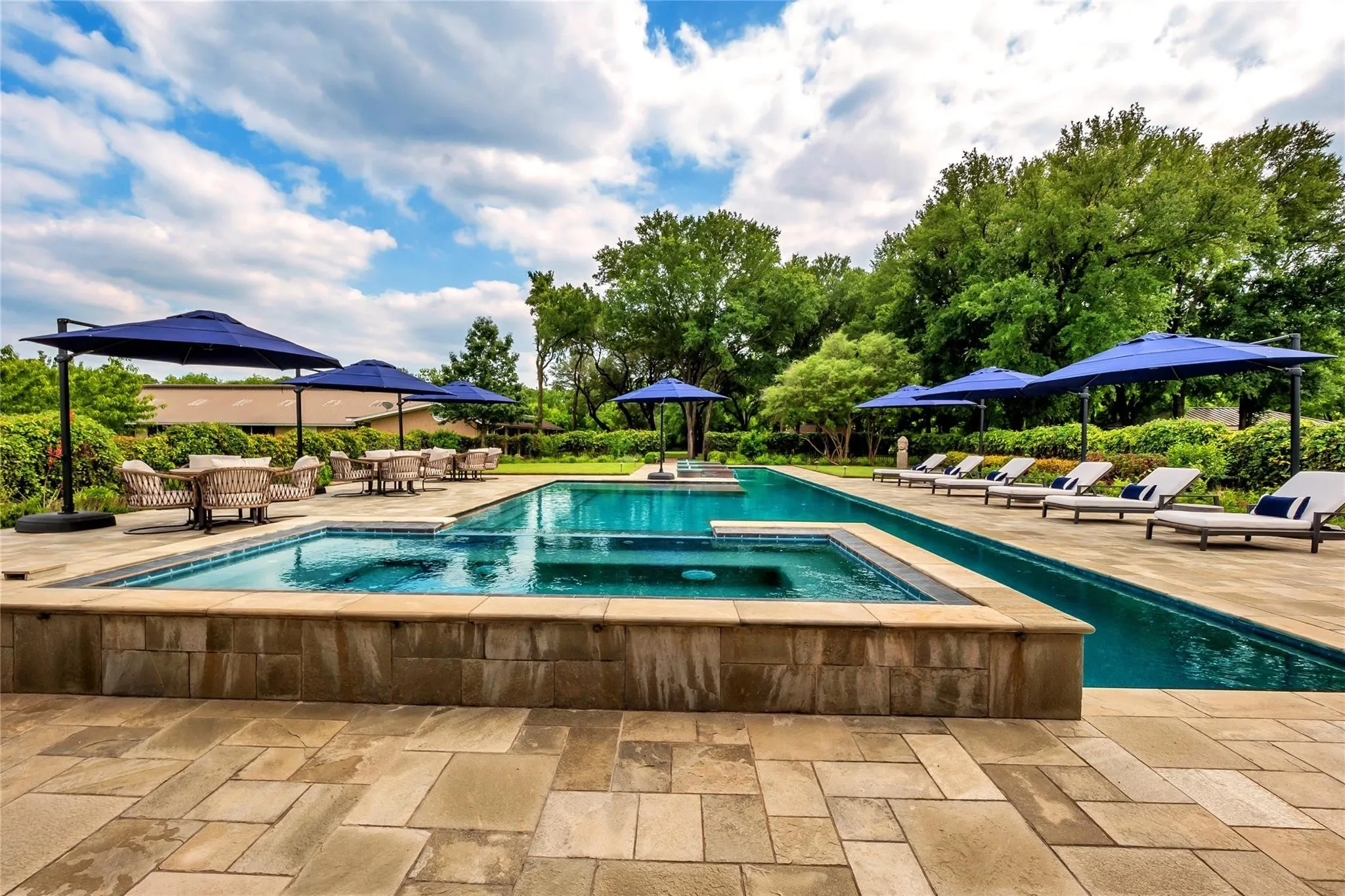 Expansive outdoor space featuring a rectangular swimming pool, integrated spa, and a flagstone patio