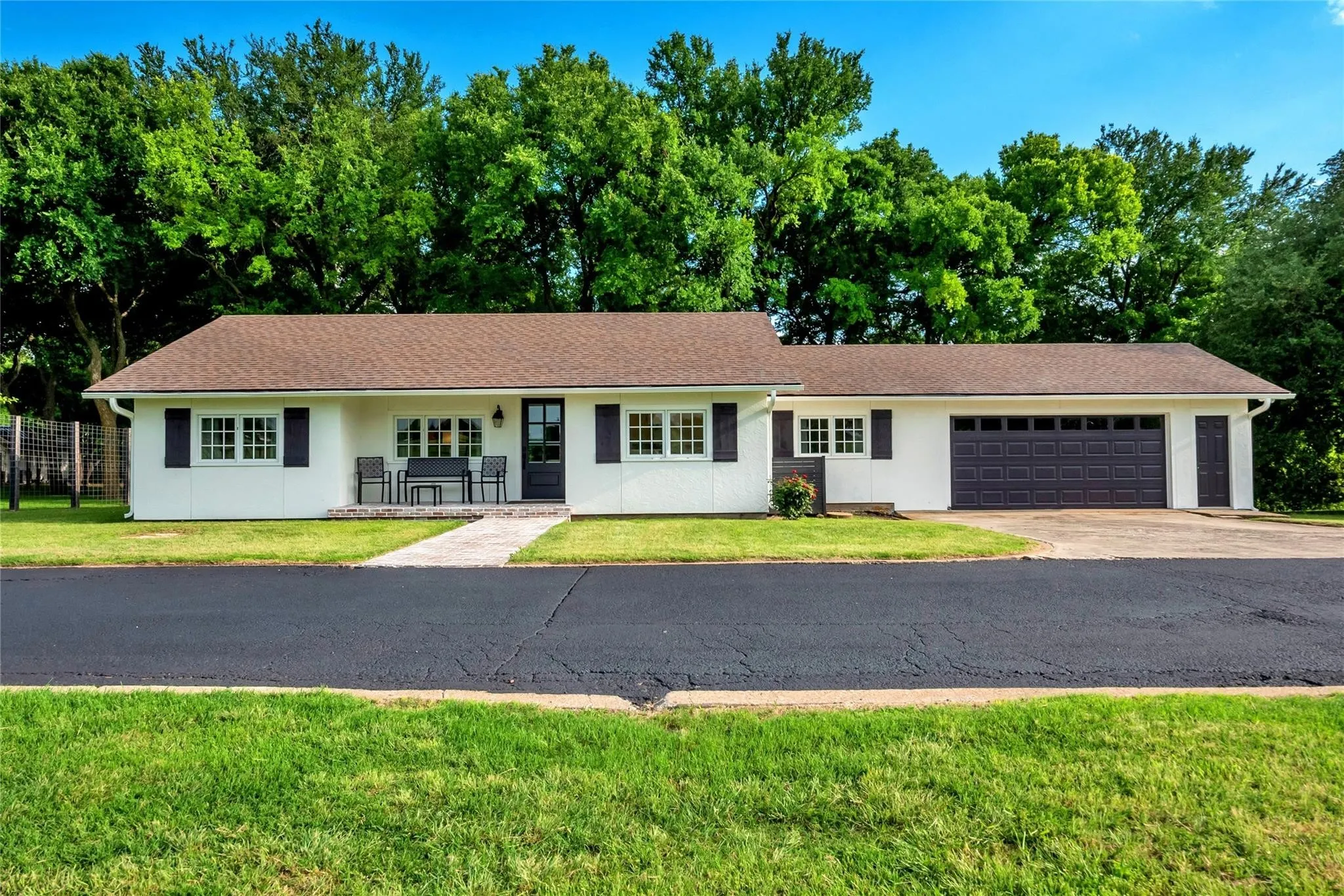 White exterior with dark shutters, two-car garage, and dark asphalt driveway
