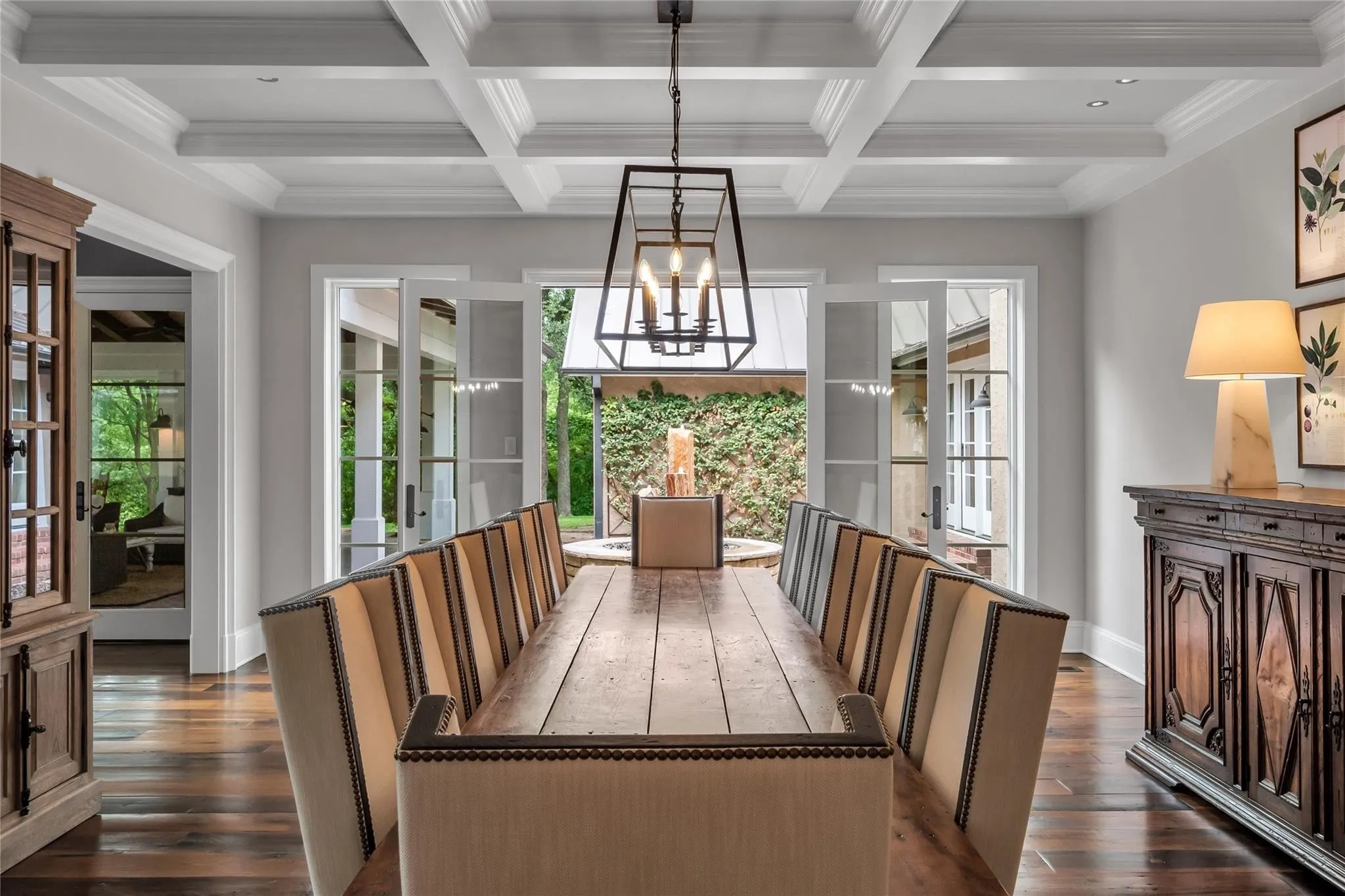 Coffered ceiling with a geometric chandelier, rich wood-finish flooring, and French doors