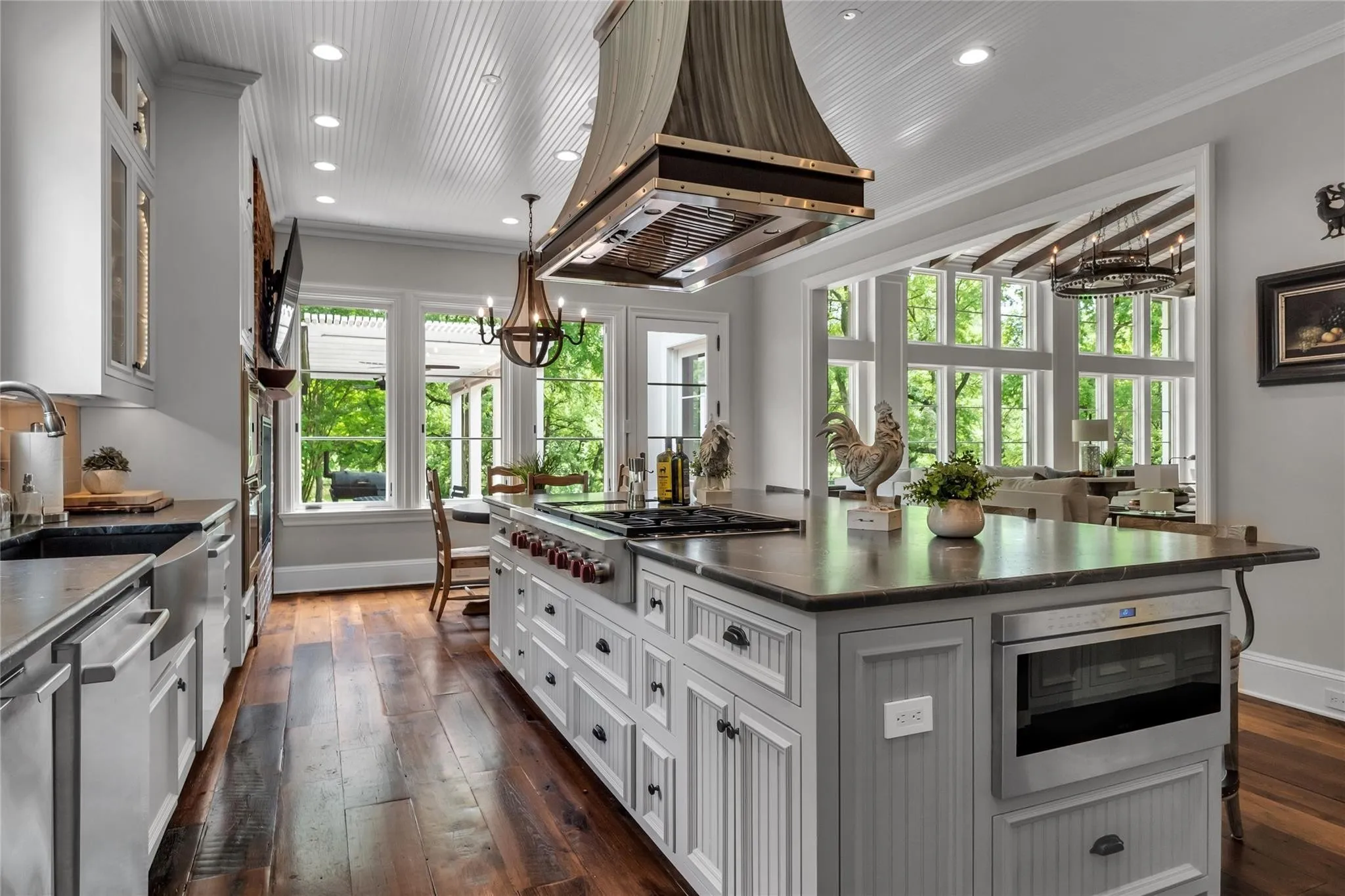 Gourmet kitchen featuring a large island, wood-finish flooring, beadboard ceiling, stainless steel appliances, and abundant natural light