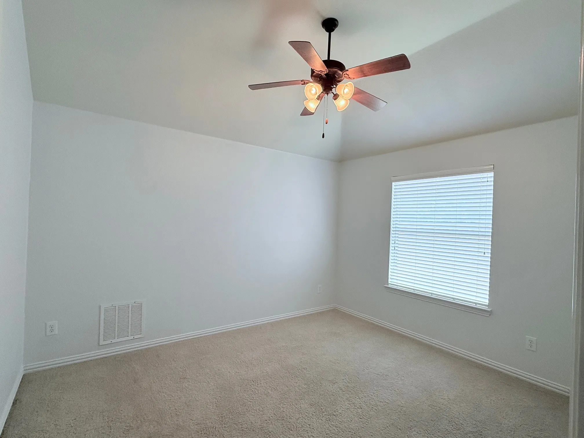 Vaulted ceiling, ceiling fan with integrated lighting, window with horizontal blinds, neutral carpet flooring, and white trim
