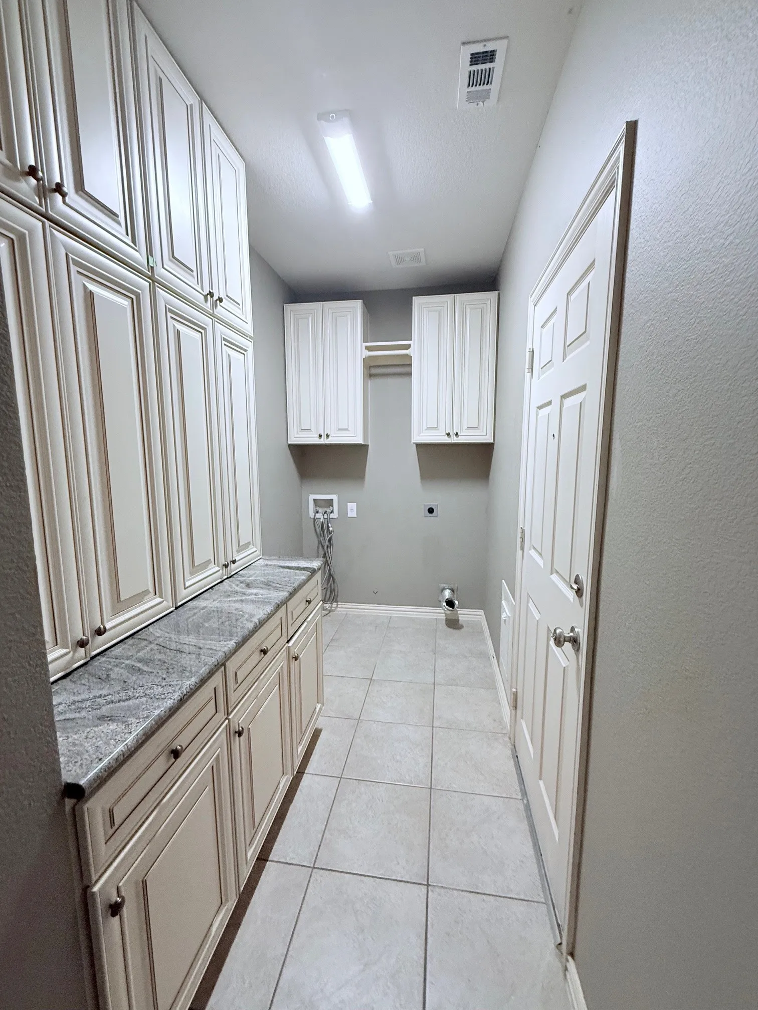 Expansive cabinetry with light-toned finishes and dark hardware, complemented by a light-colored countertop