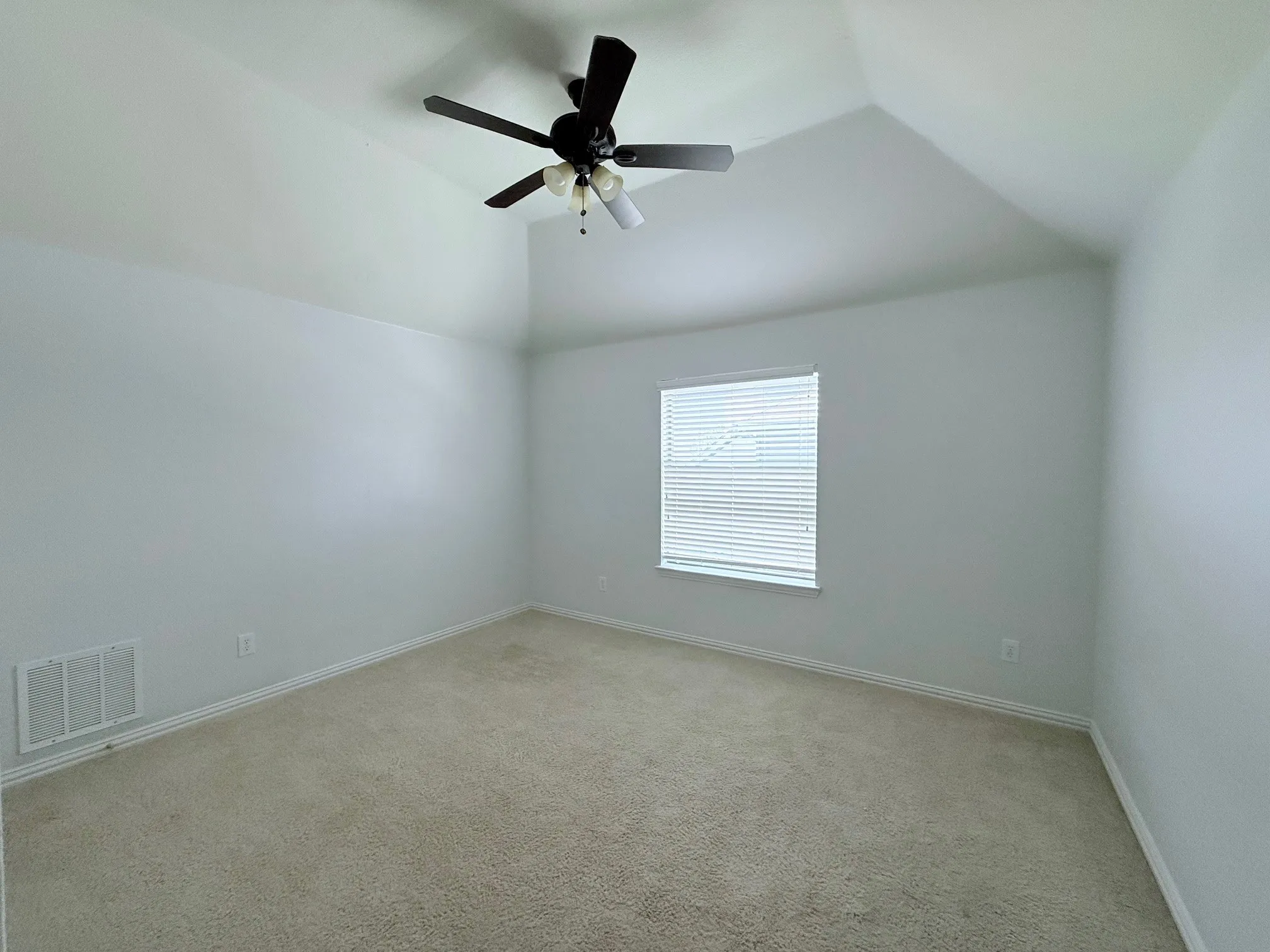 Vaulted ceiling with a black ceiling fan, neutral wall paint, window with blinds, and light-colored carpeting