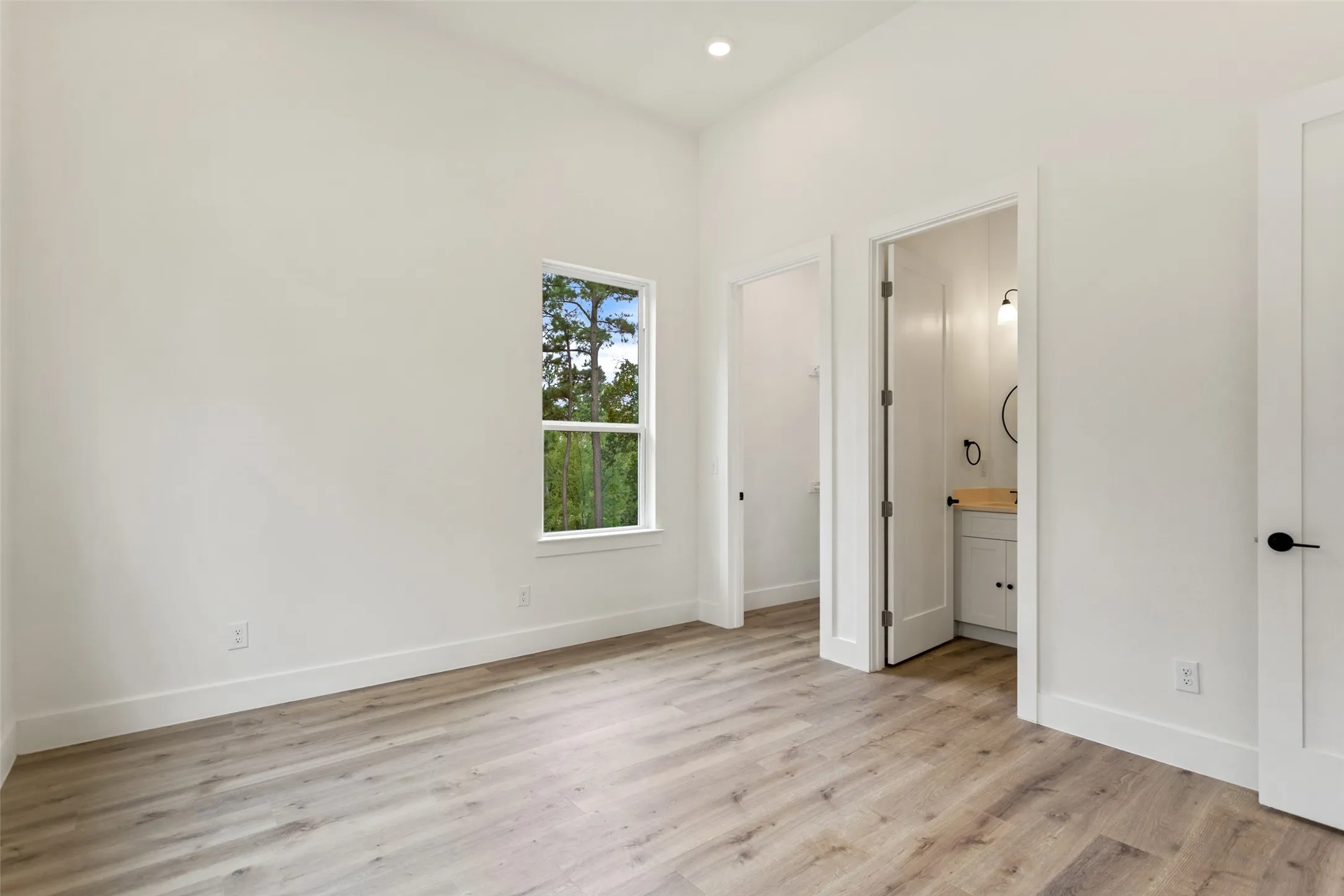 Recessed lighting, wood-finish flooring, white walls, white trim, and a white vanity with a wooden countertop