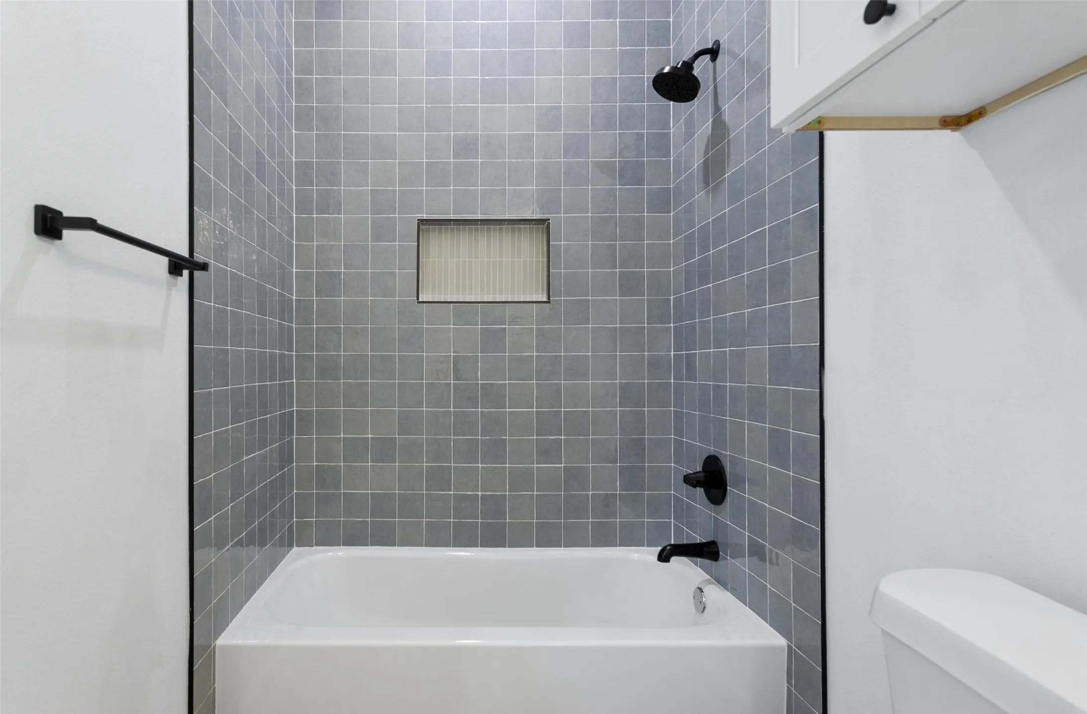 Integrated bathtub with tiled surround featuring a recessed niche