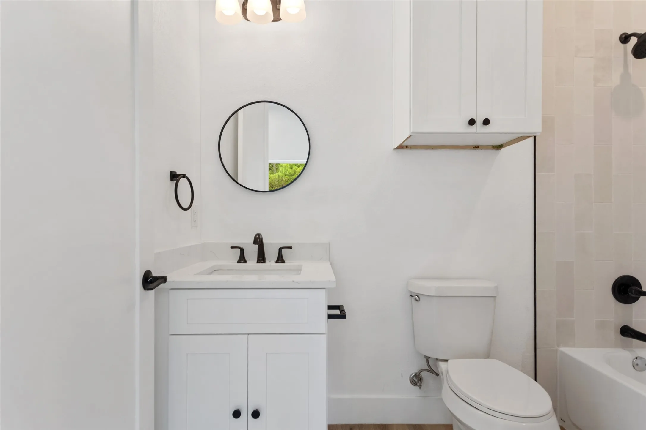 White vanity with an integrated sink and matte black faucet, illuminated by an overhead light fixture