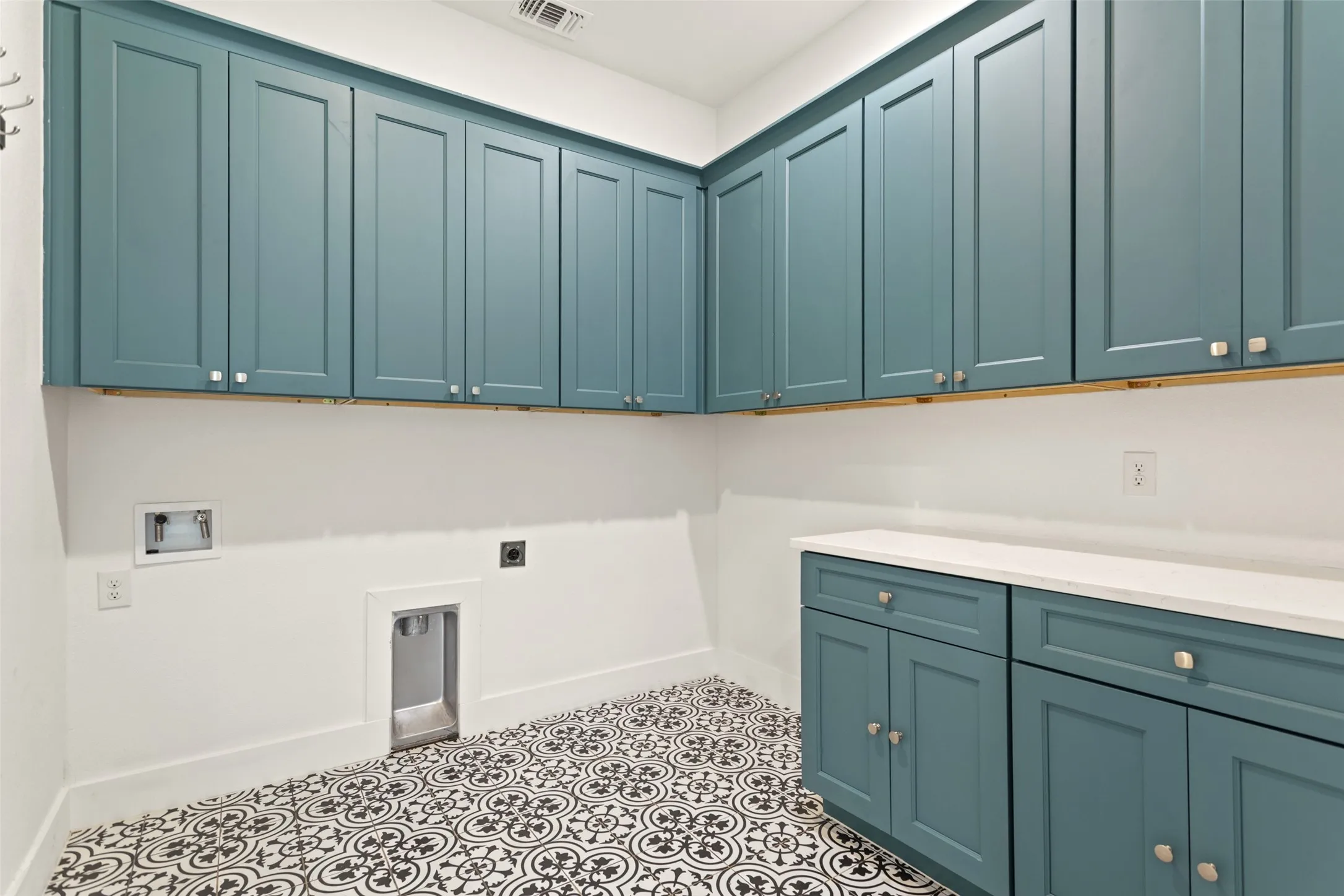 Extensive cabinetry with a blue finish, white countertops, and patterned floor tile