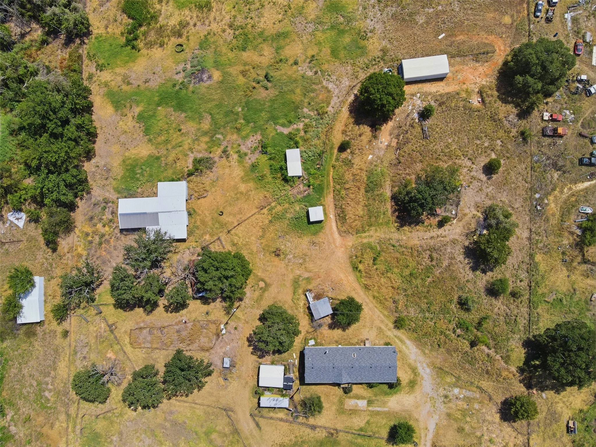 Extensive property with multiple outbuildings, including a primary residence with a dark shingle roof and a metal-roofed structure