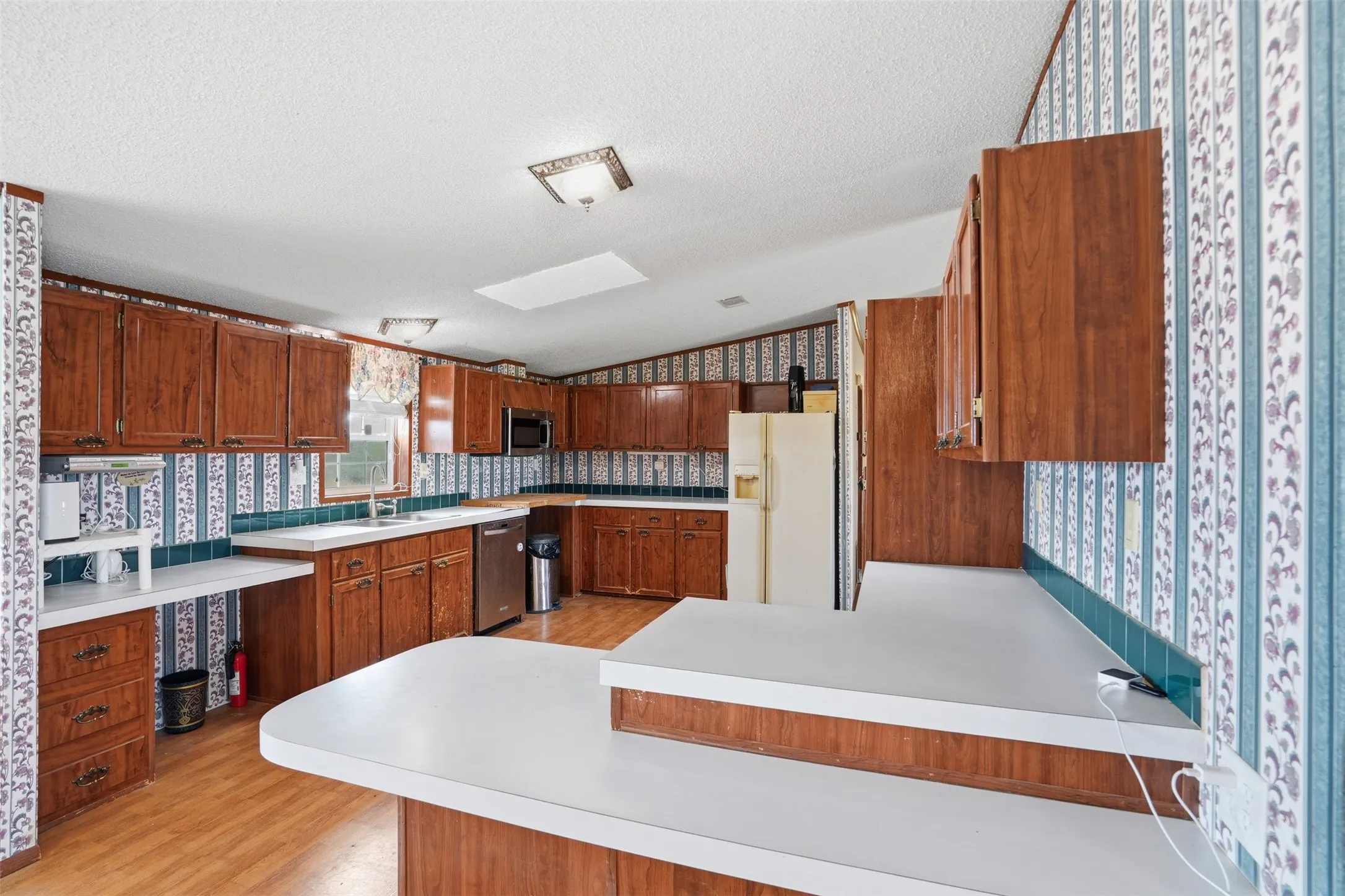 Kitchen featuring wood-finish cabinetry, white countertops, tile backsplash, and wood-finish flooring