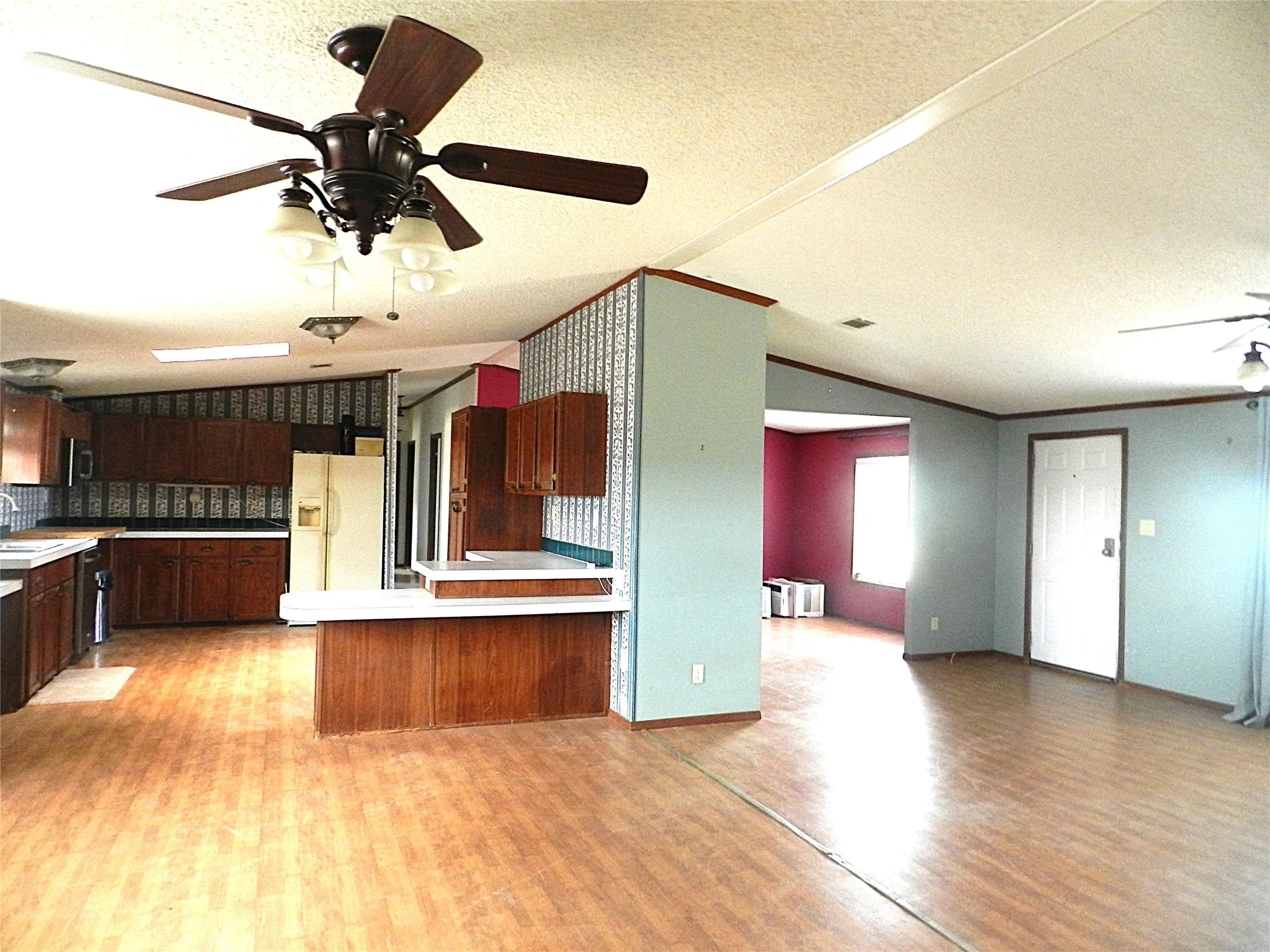 Open concept living space featuring wood-finish flooring, a kitchen with wood cabinetry, and a ceiling fan