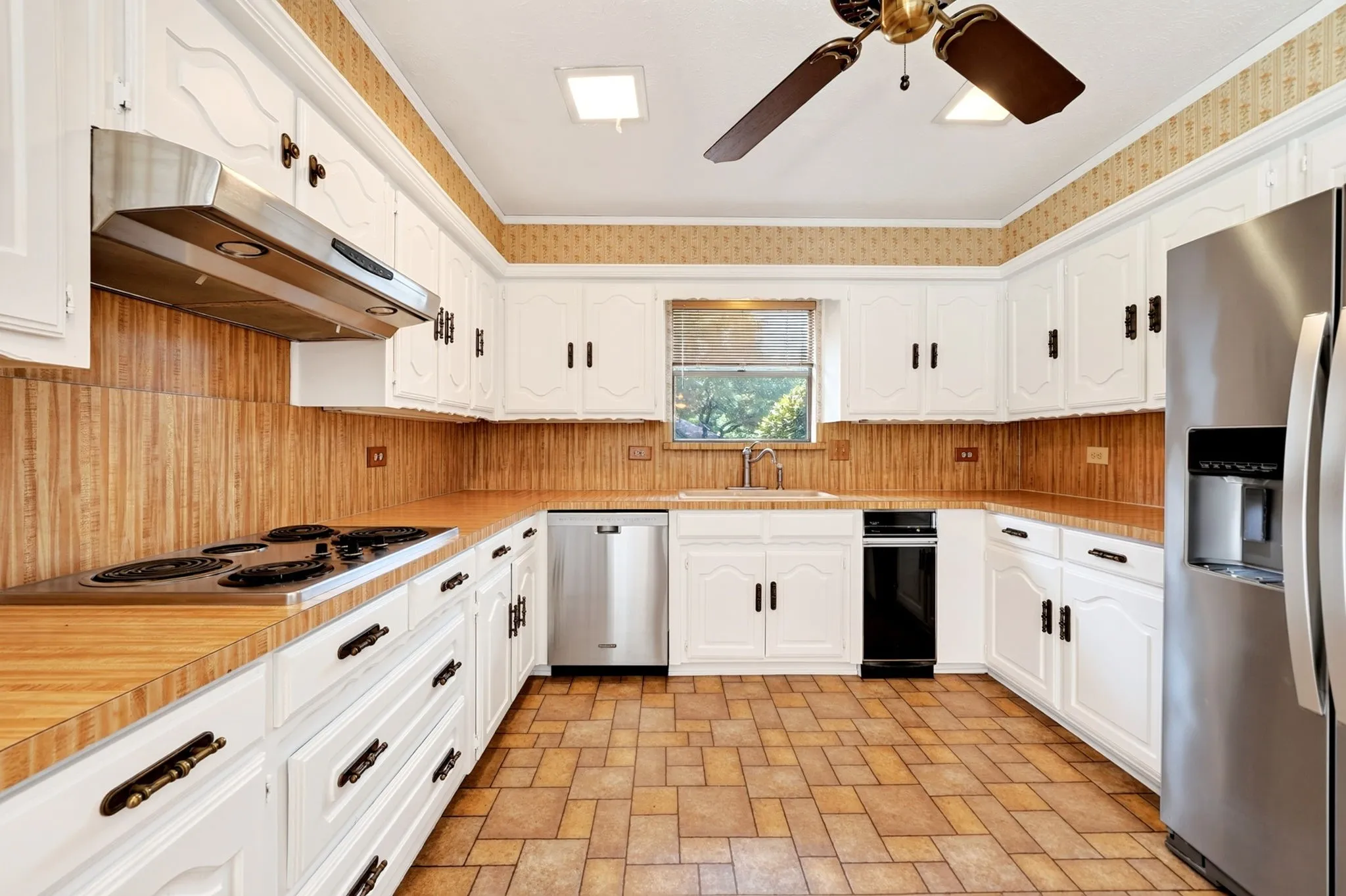 U-shaped kitchen featuring white cabinetry, patterned floor tiling, and a stainless steel refrigerator