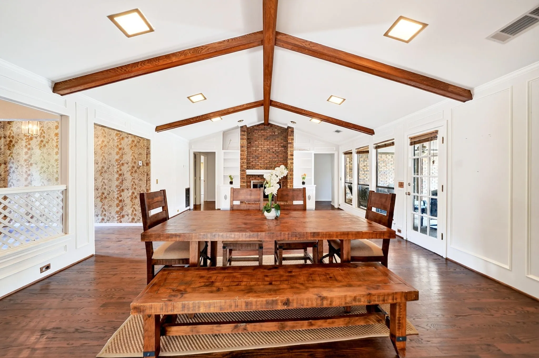 Vaulted ceiling with exposed wood beams, recessed lighting, and wood-finish flooring
