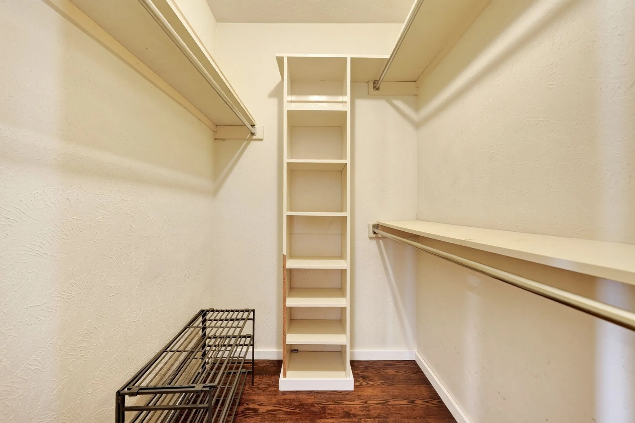 Walk-in closet with built-in shelving, hanging rods, and wood-finish flooring