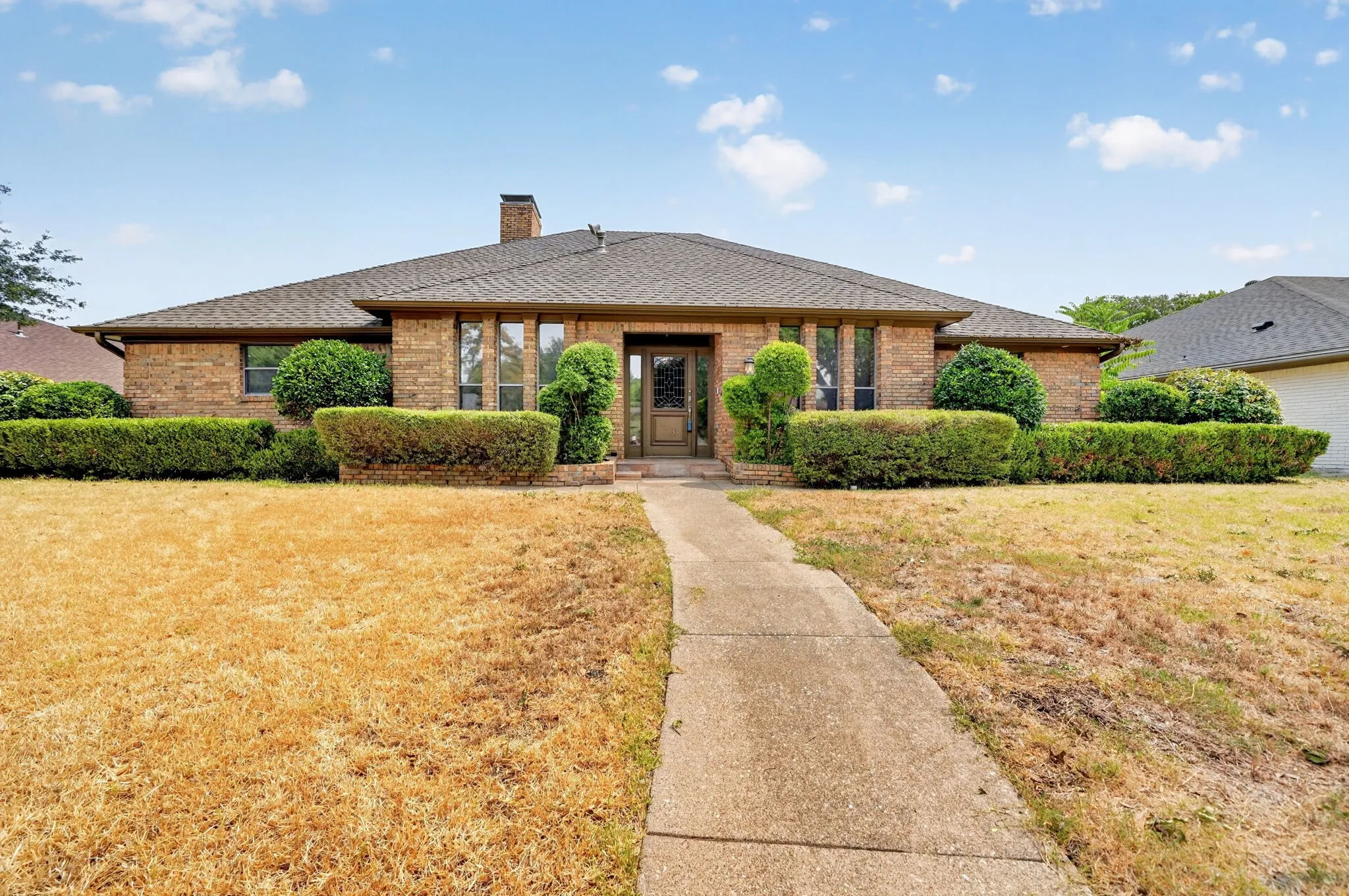 Brick exterior featuring a gabled roof, prominent chimney, and a concrete pathway leading to the entrance
