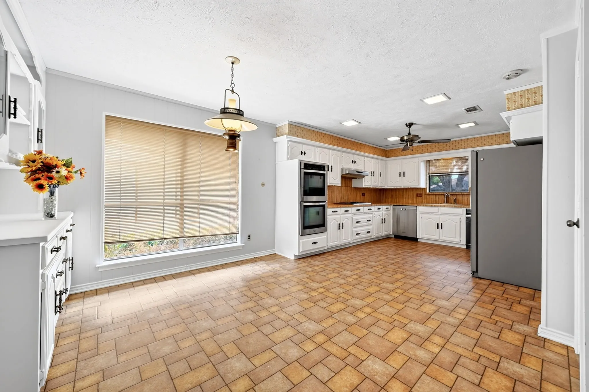 Kitchen featuring white cabinetry, double wall ovens, a stainless steel dishwasher, and a ceiling fan