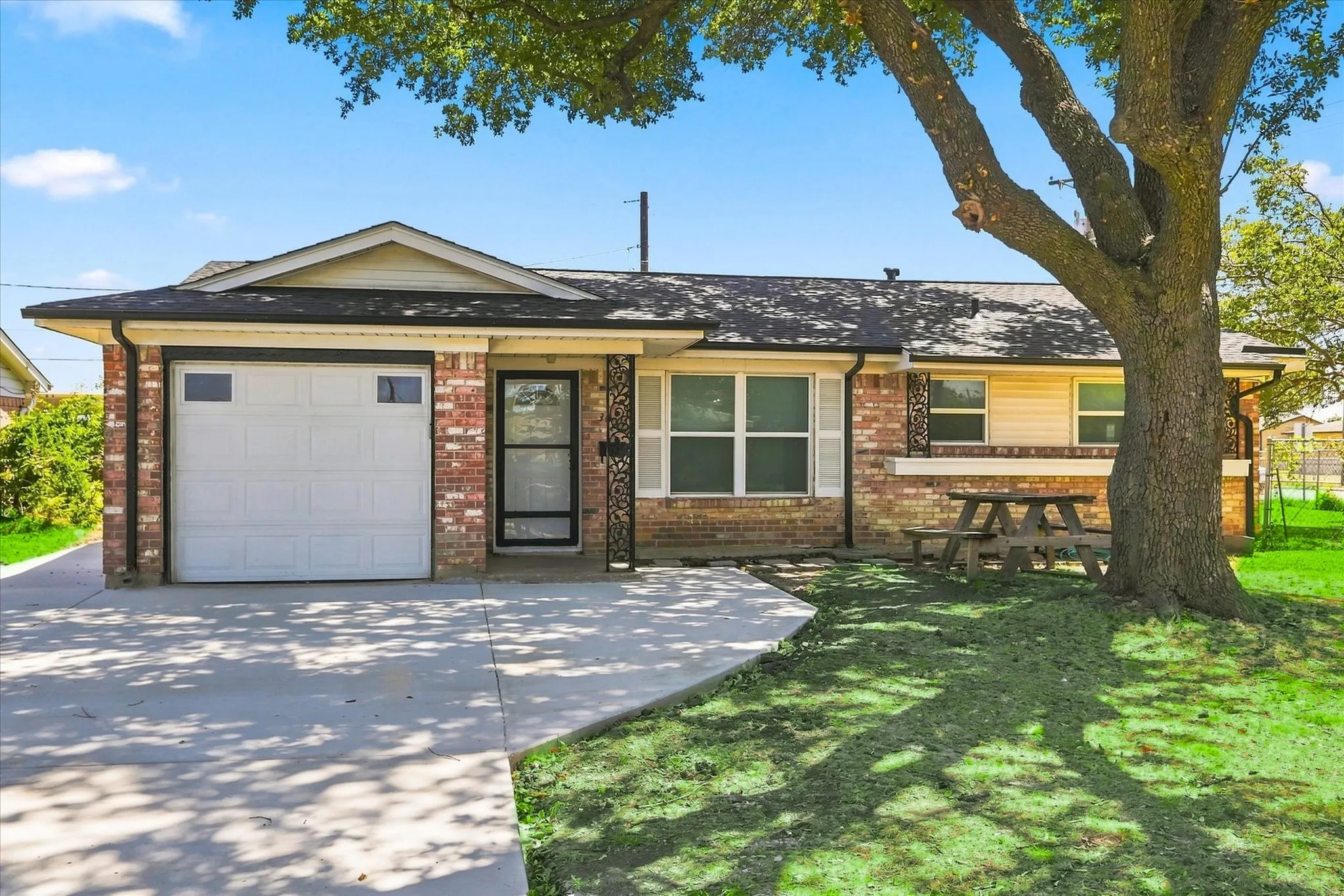 Brick exterior with partial siding, attached single-car garage, and a concrete driveway