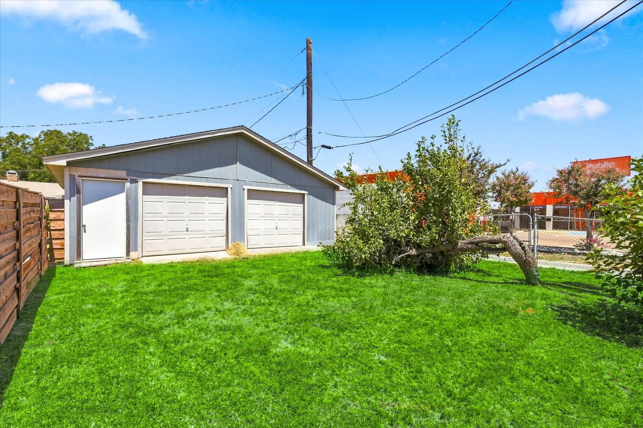 Detached garage with two roll-up doors, an additional side entry door, and a privacy fence