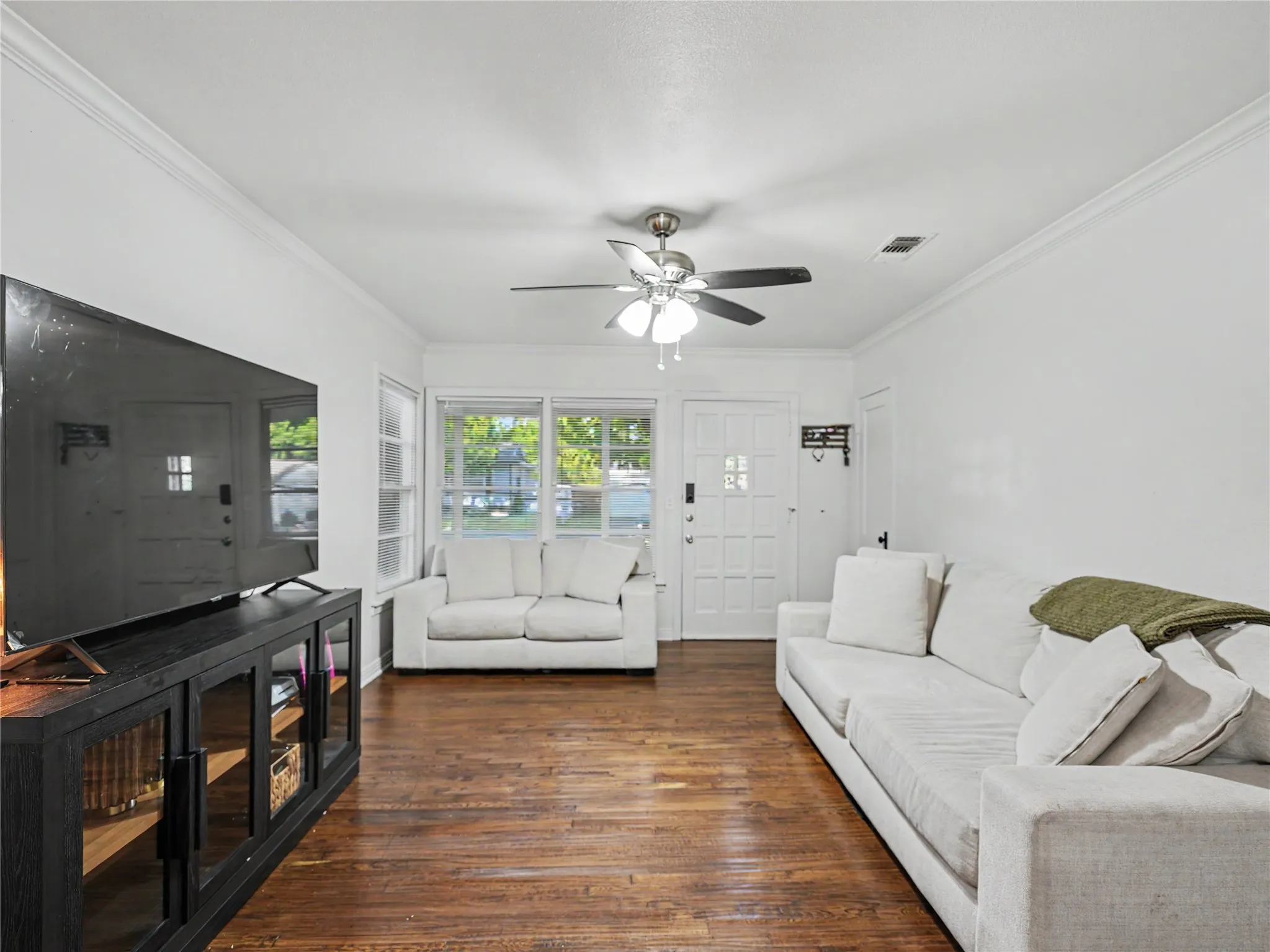 Wood-finish flooring, white walls, crown molding, and a ceiling fan with integrated lighting