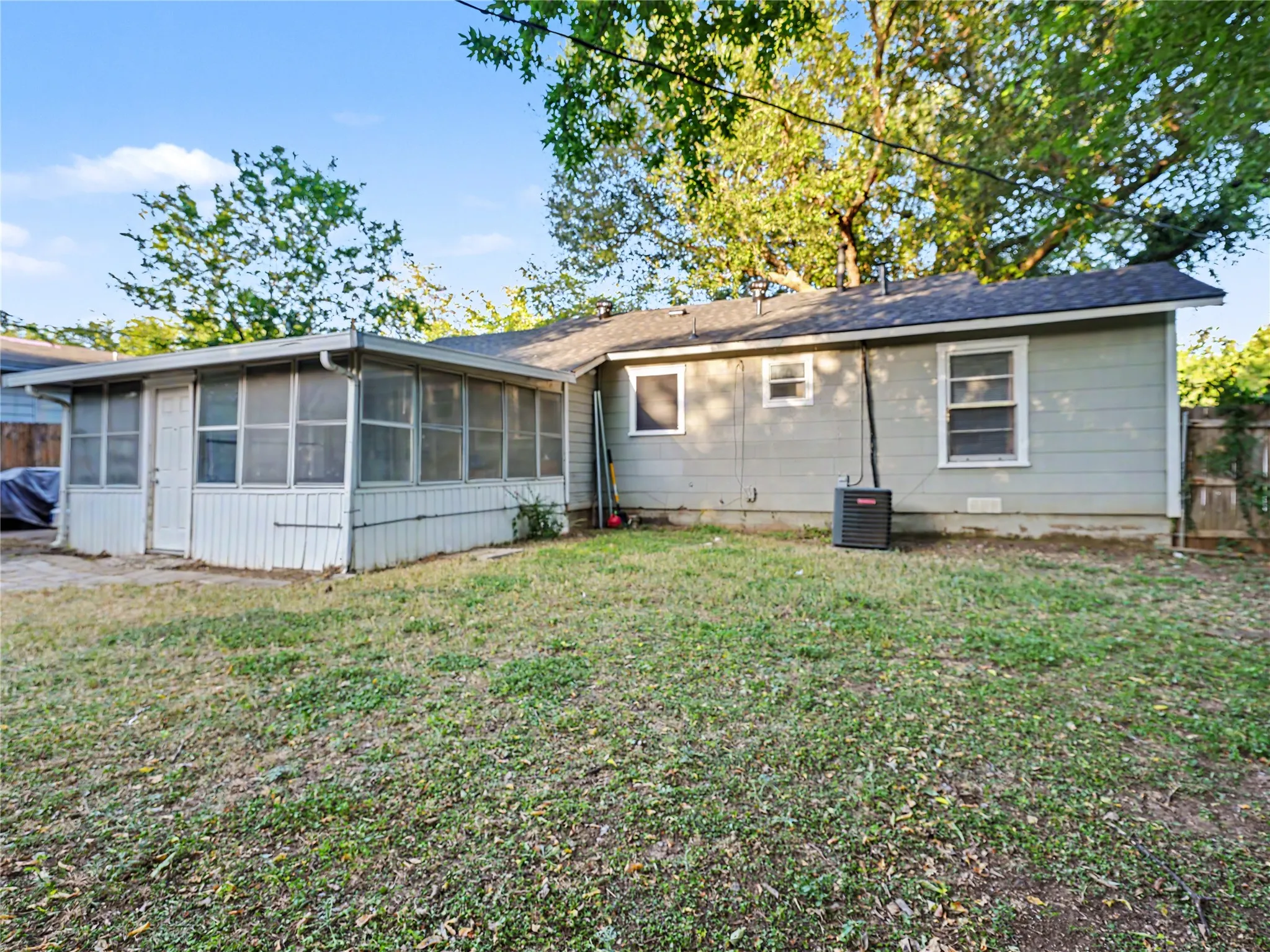 Rear exterior with a screened-in porch, light-colored siding, and a dark shingle roof
