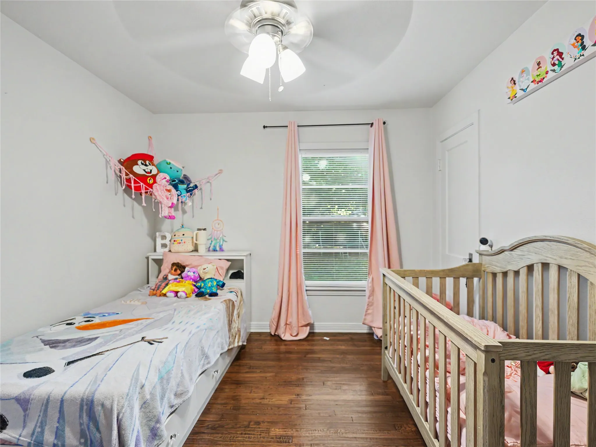 Tray ceiling with a ceiling fan, recessed window, white door, and wood-finish flooring