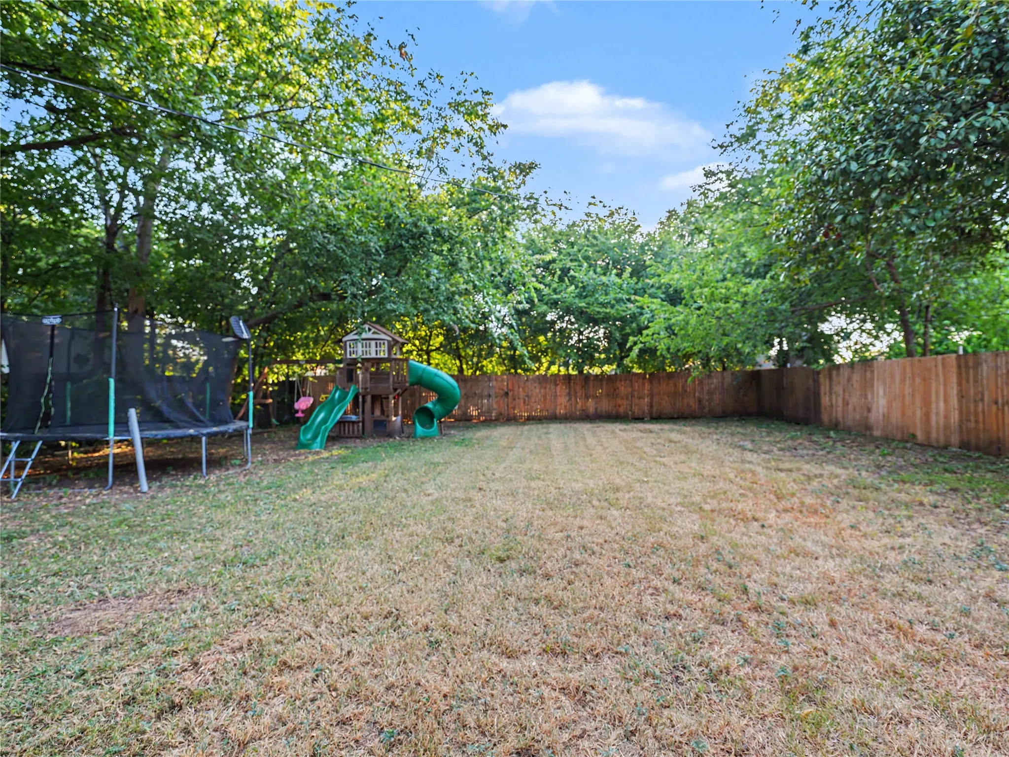 Expansive backyard with a wood privacy fence and mature trees
