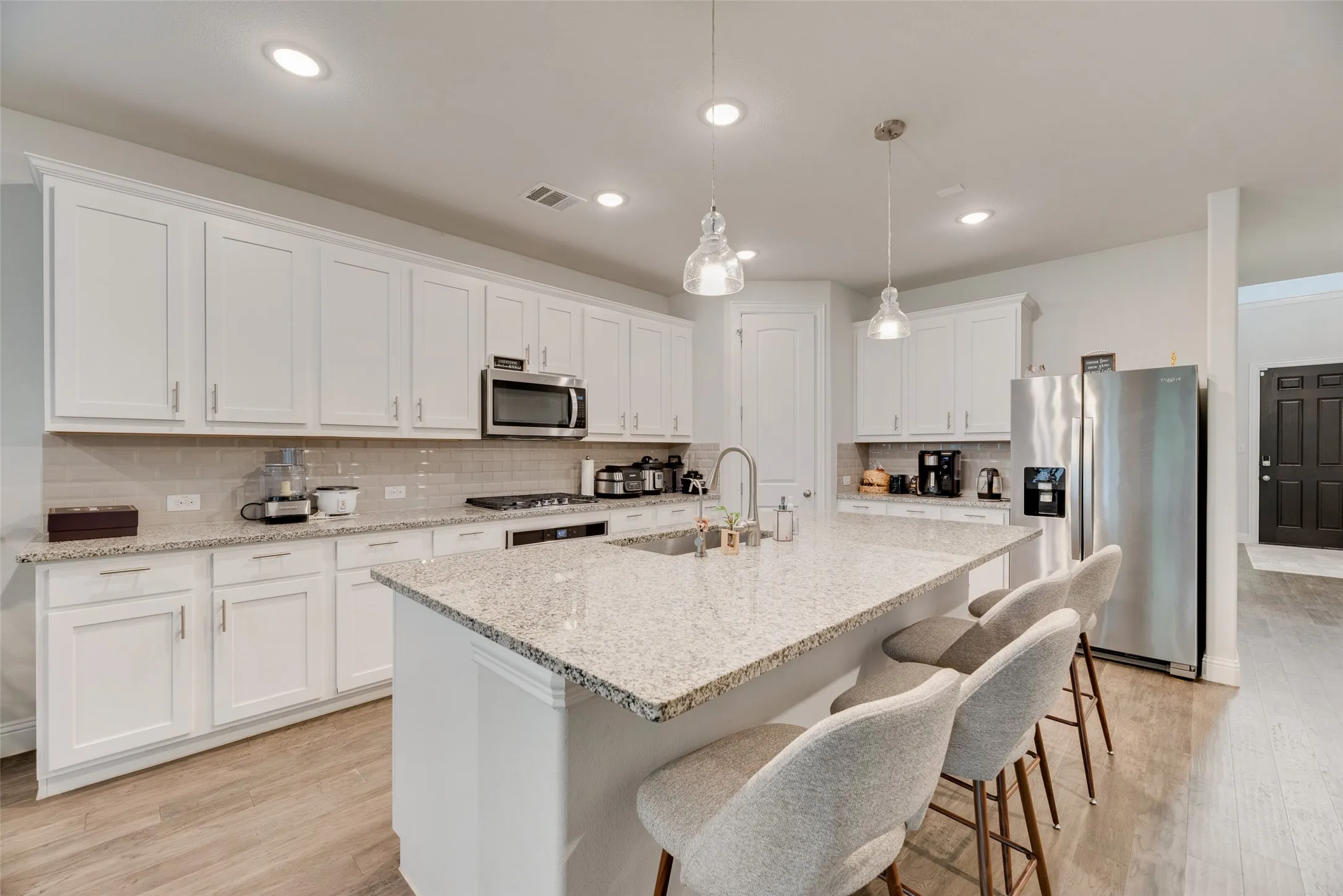 Kitchen with white cabinets, a sink, stainless steel appliances, backsplash, and visible vents