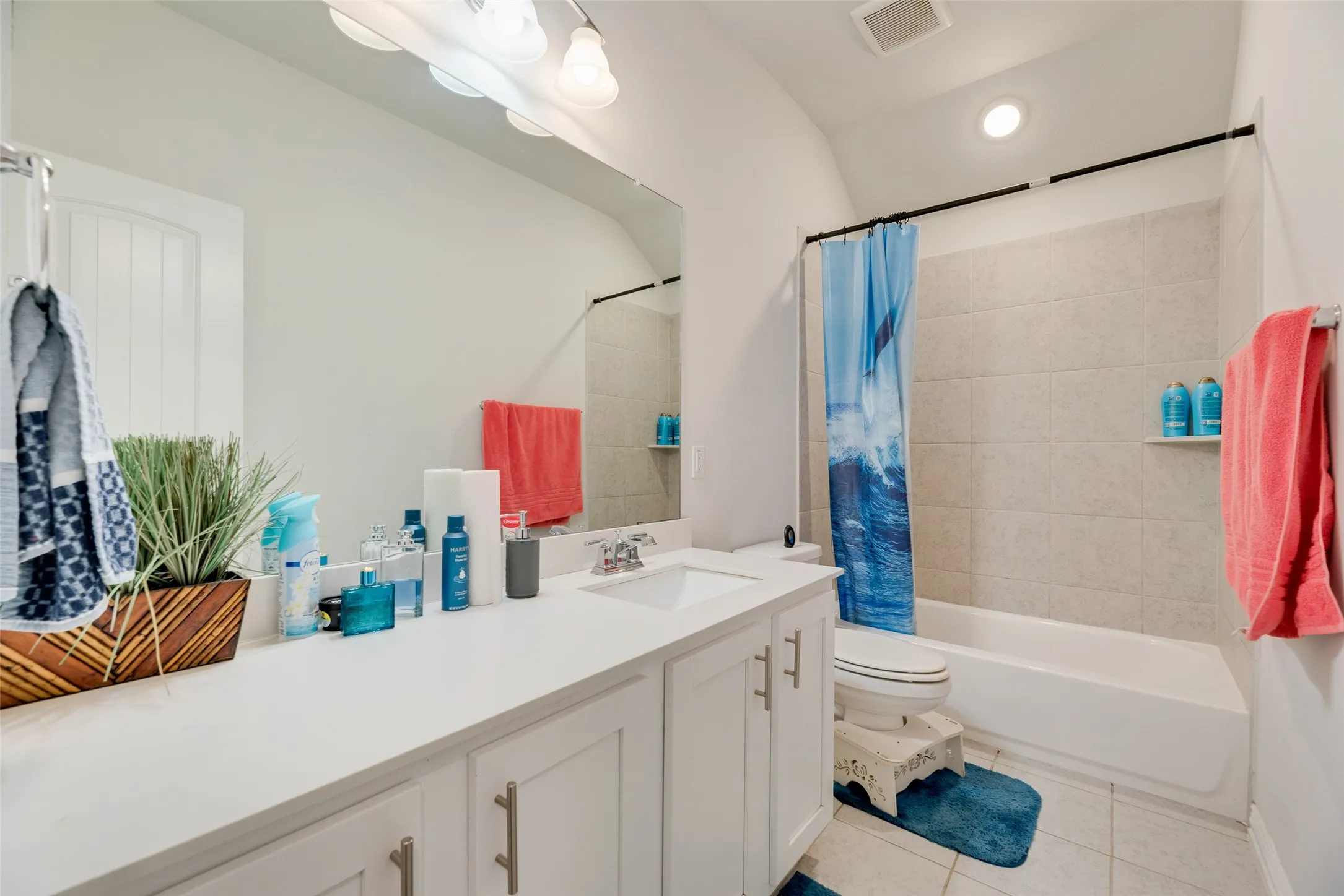 Full bathroom with visible vents, shower / bath combo with shower curtain, tile patterned flooring, vanity, and toilet