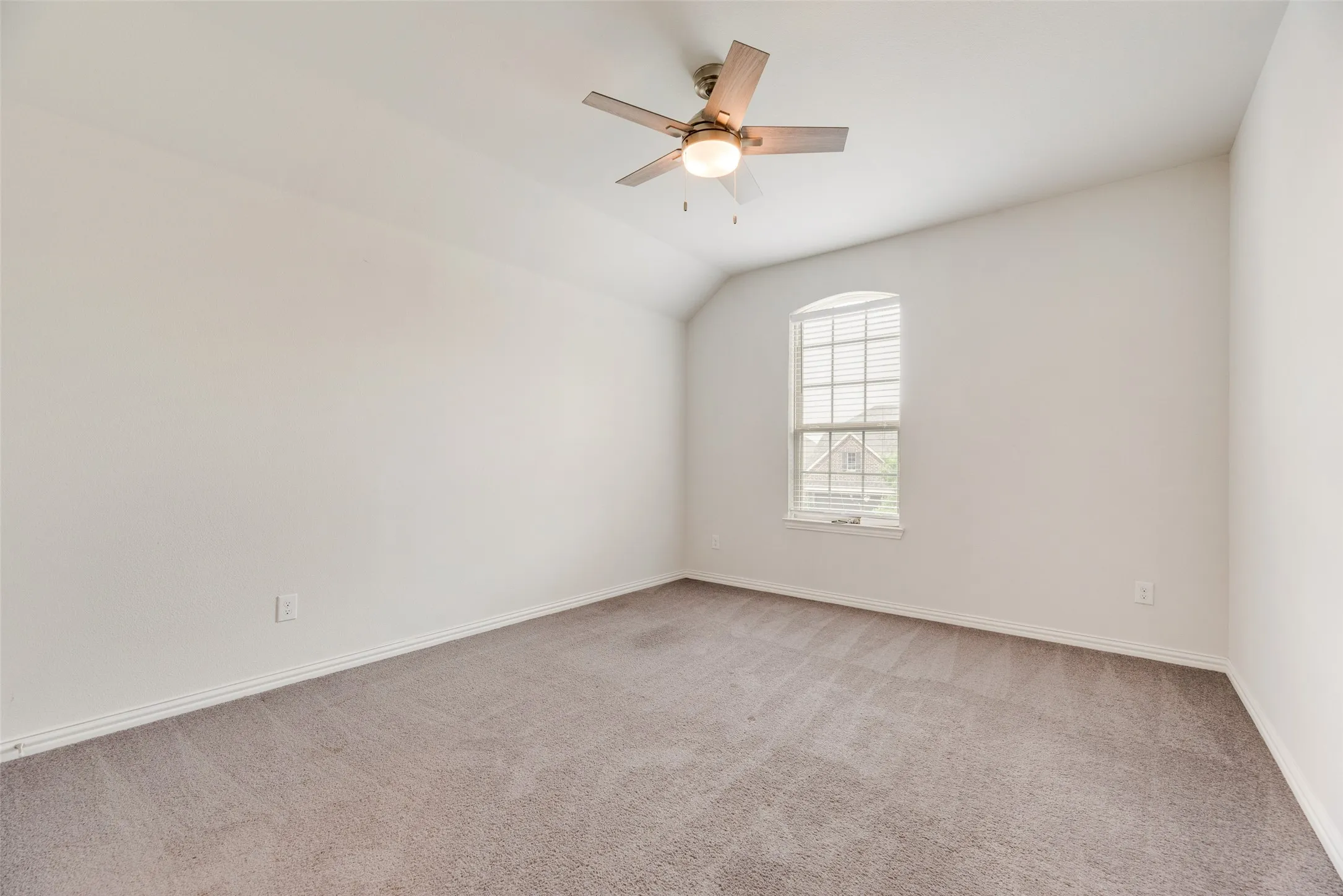 Spare room with baseboards, ceiling fan, carpet, and vaulted ceiling