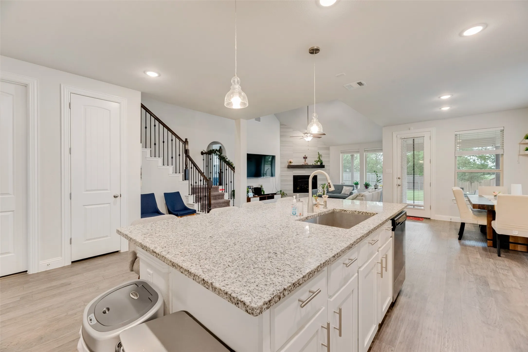 Kitchen featuring visible vents, a large fireplace, a sink, and light wood-style flooring