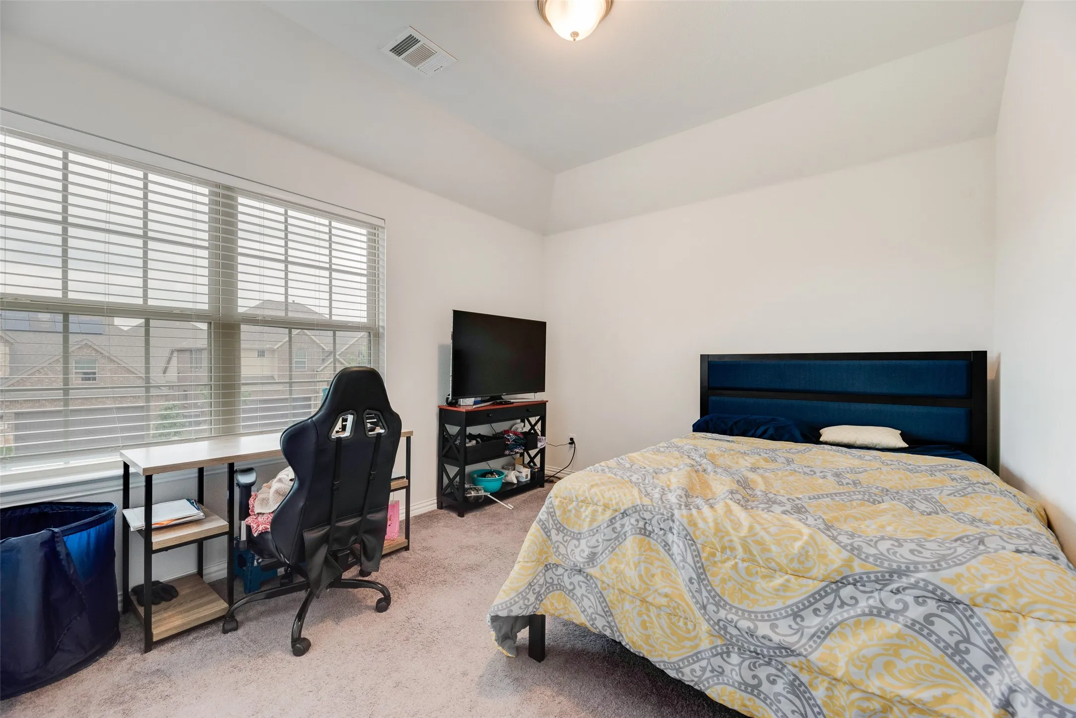 Carpeted bedroom with visible vents and lofted ceiling