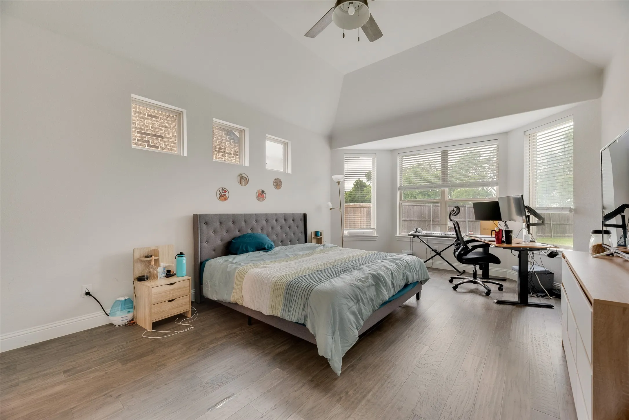 Bedroom with baseboards, ceiling fan, wood finished floors, and high vaulted ceiling