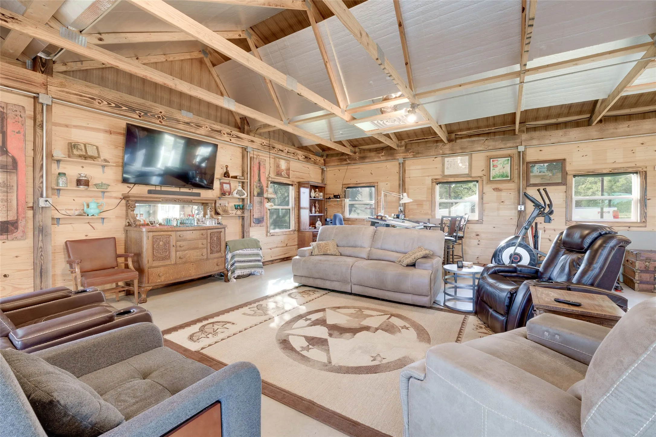Spacious room with wood plank walls, exposed wood beam ceiling, and multiple windows