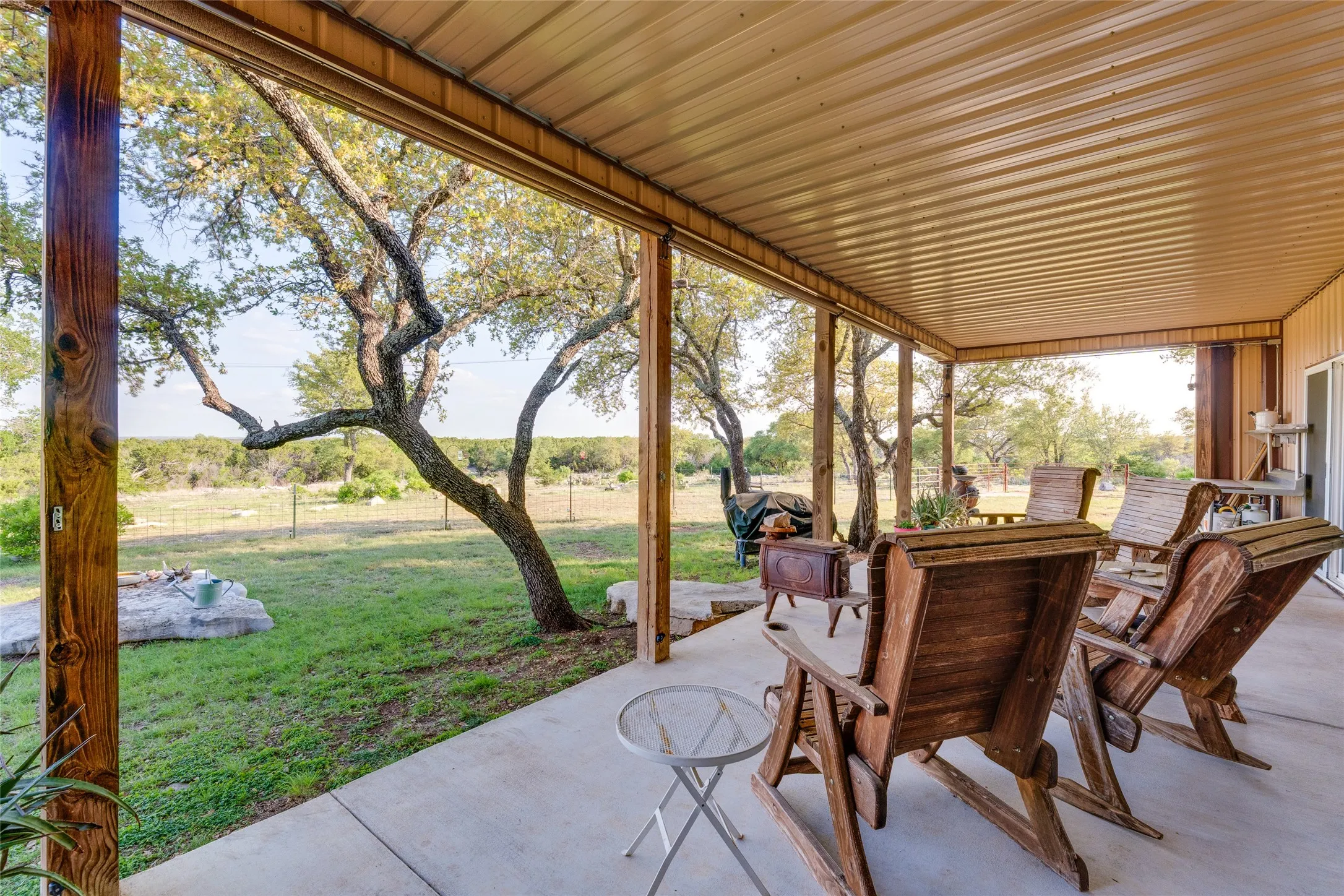 Covered outdoor patio with a concrete surface, wood-clad support beams, and a corrugated metal ceiling