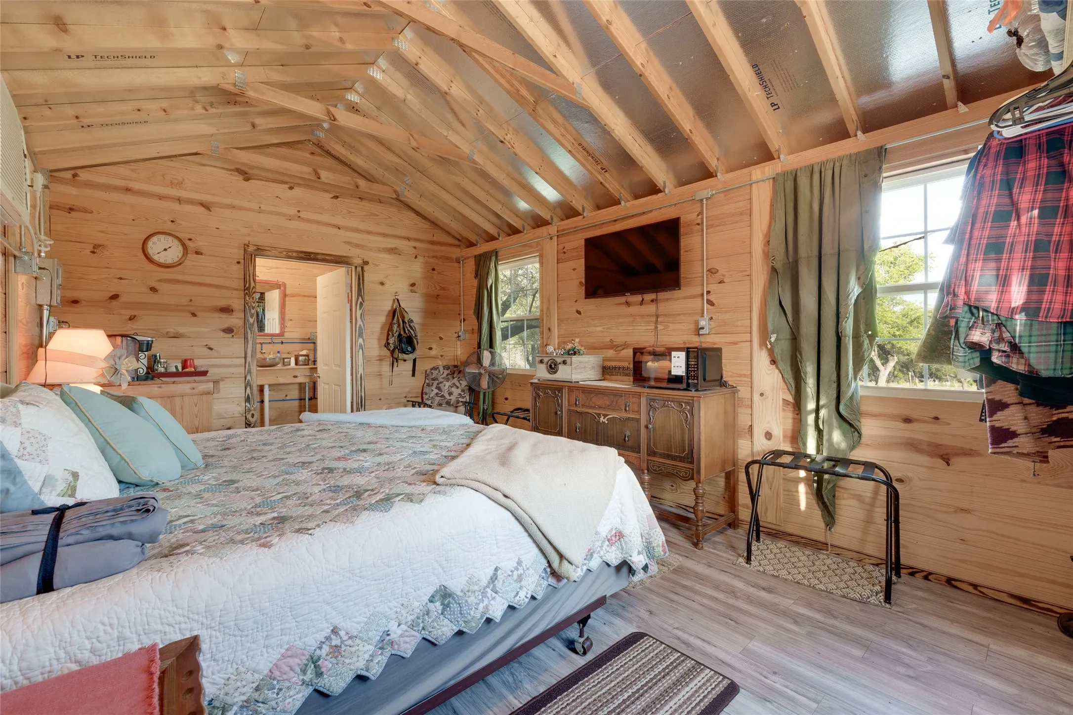Wood-finish flooring, wood-paneled walls, exposed beam vaulted ceiling, and an interior window