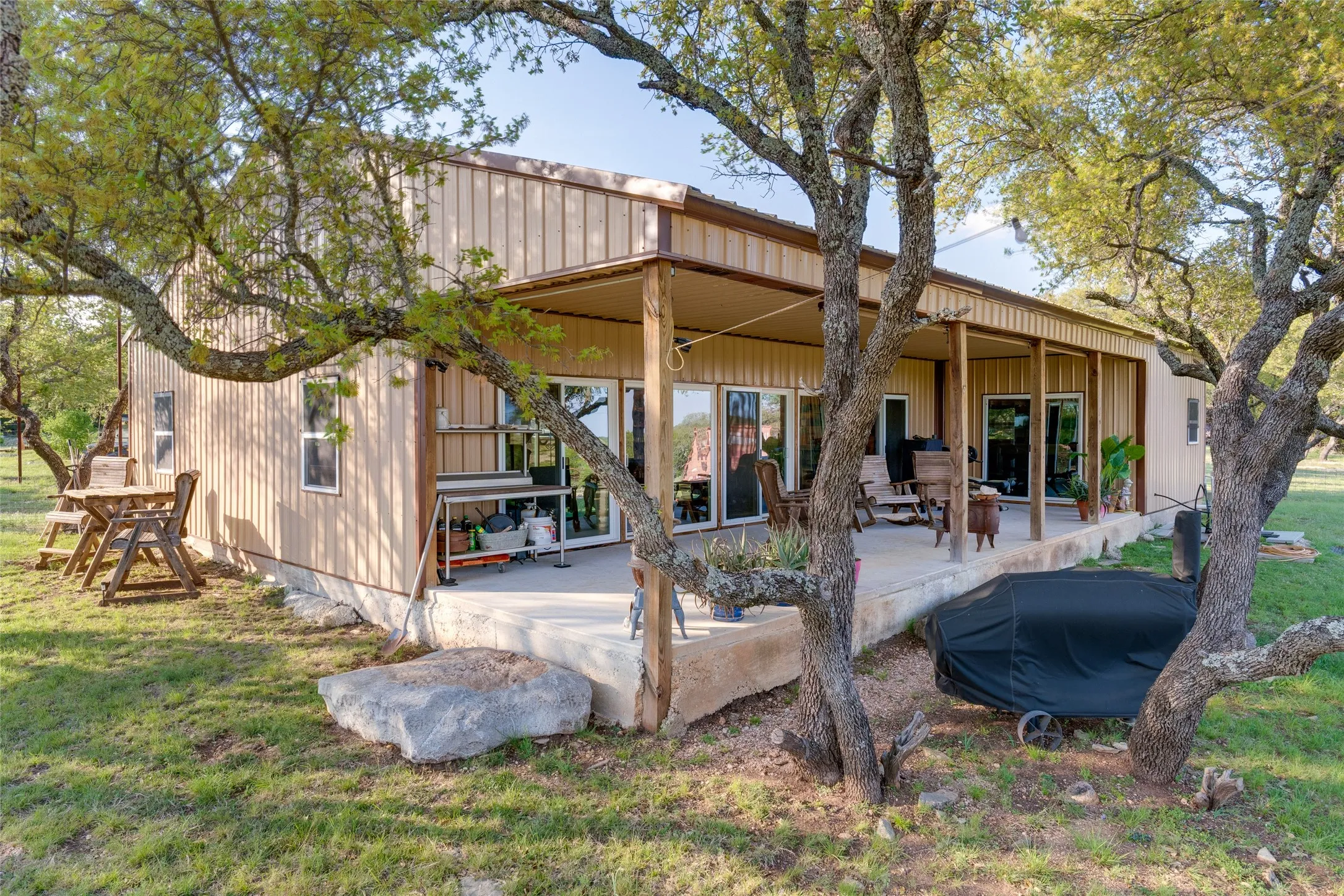 Exterior featuring vertical panel siding, a covered porch, and multiple glass sliding doors