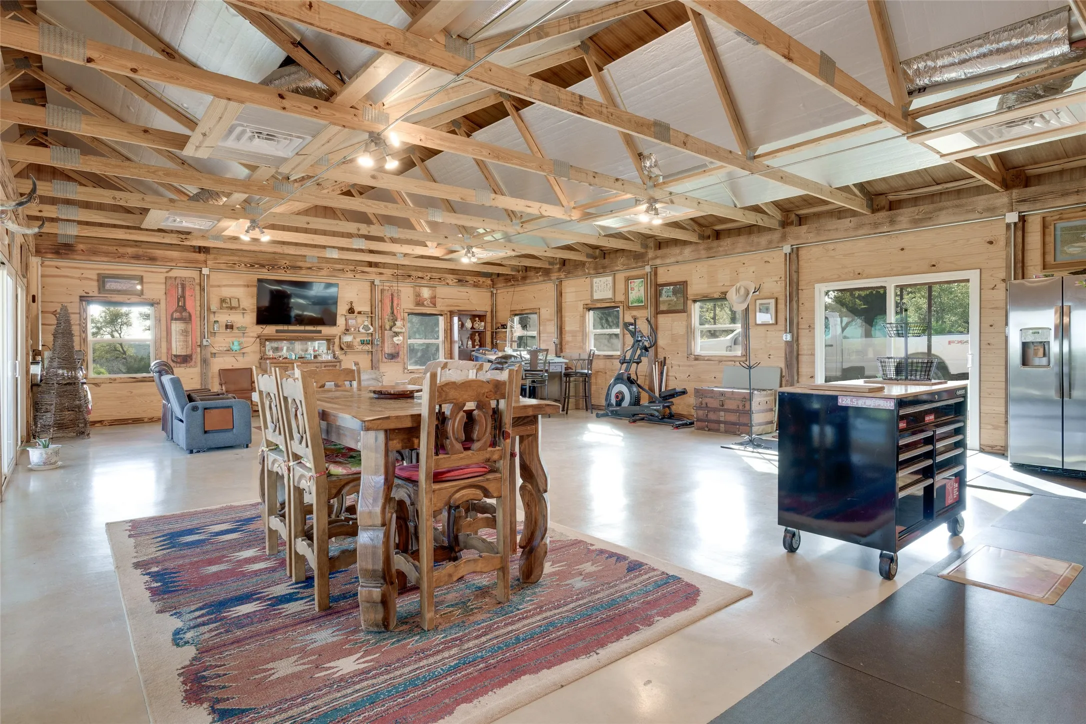 Exposed beam ceiling, wood-paneled walls, concrete flooring, stainless steel refrigeration, and sliding glass doors