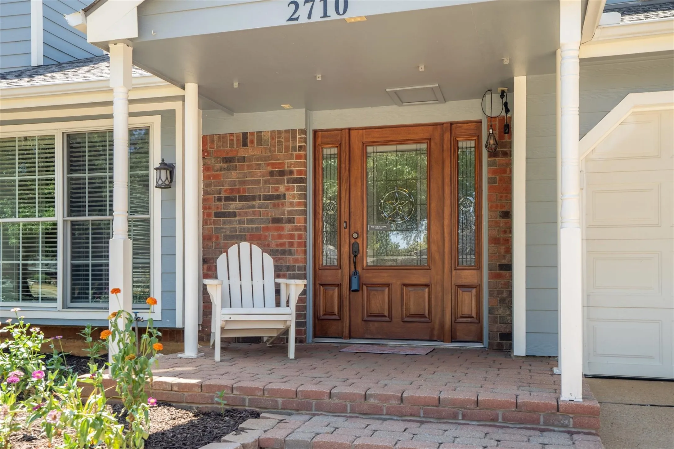 Welcoming covered front porch with a solid wood entry door — the perfect spot to unwind