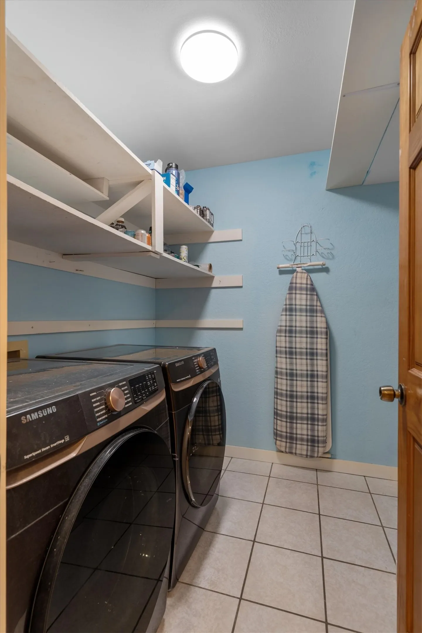 Convenient laundry room with built-in shelving and tile flooring