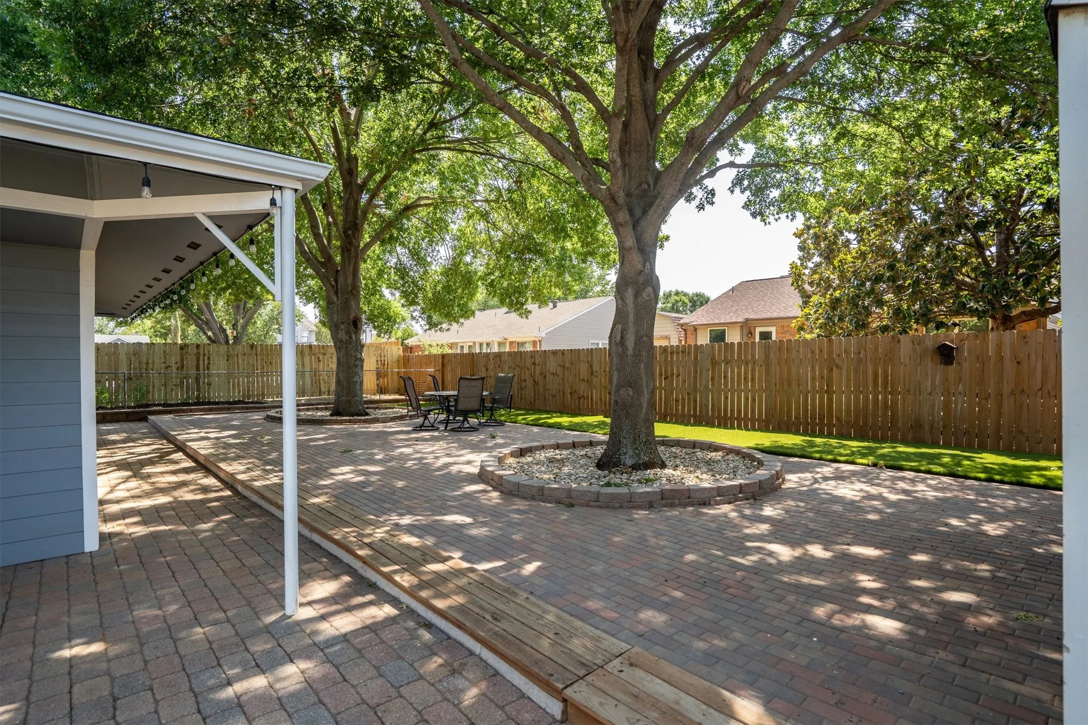 Covered patio area surrounded by mature trees — a serene outdoor retreat