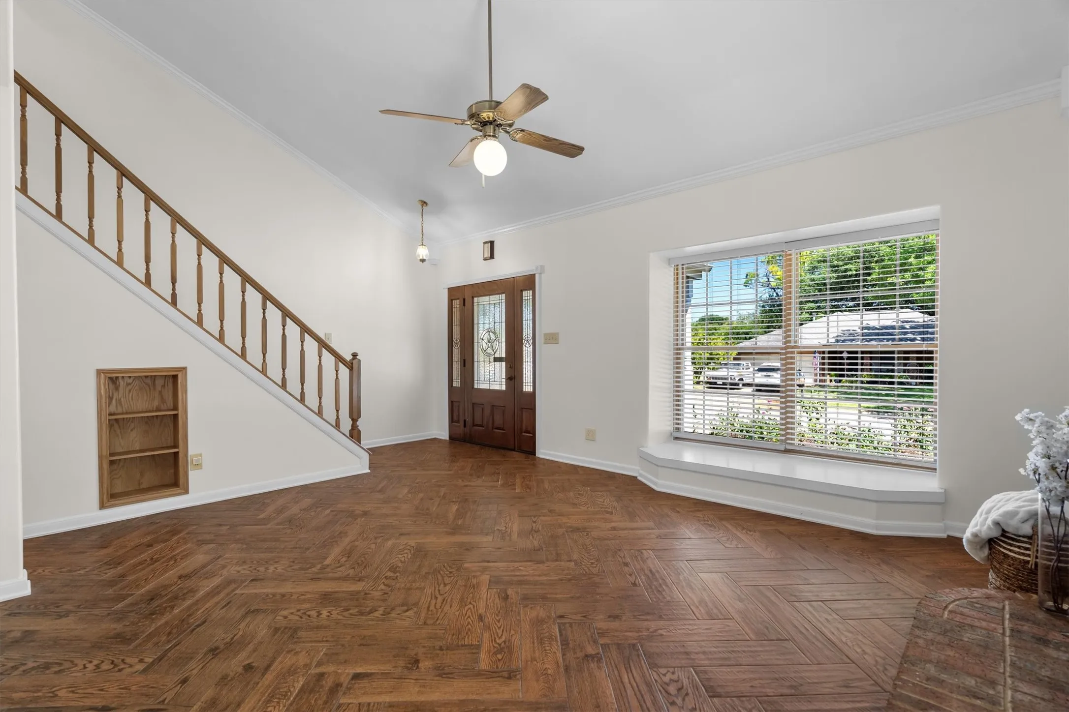 Bright entryway open to the staircase, with a cozy window seat and wood flooring throughout