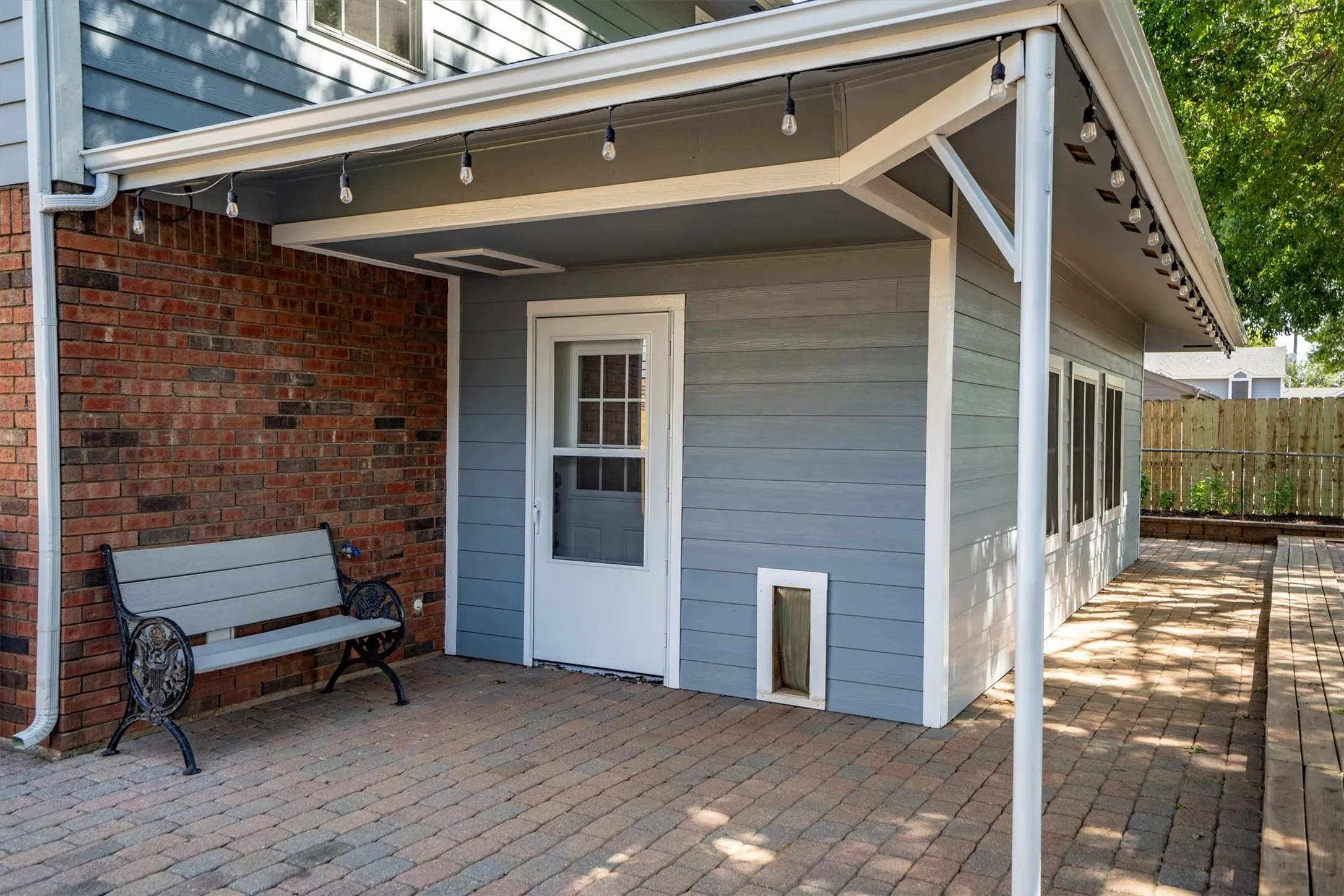 Covered back patio with brick accents and built-in pet door — great indoor-outdoor flow