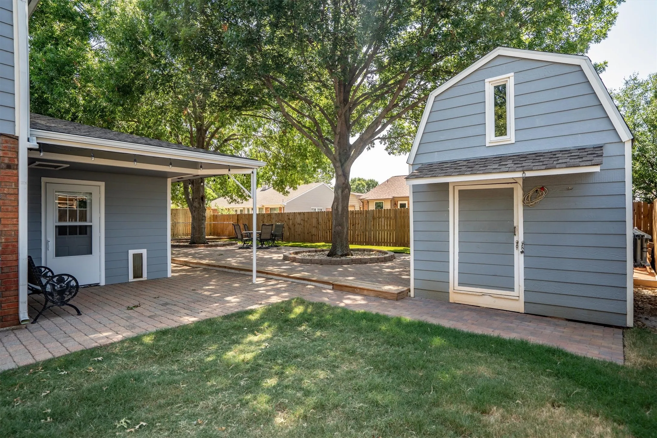 Backyard storage shed with charming dormer accent and covered walkway
