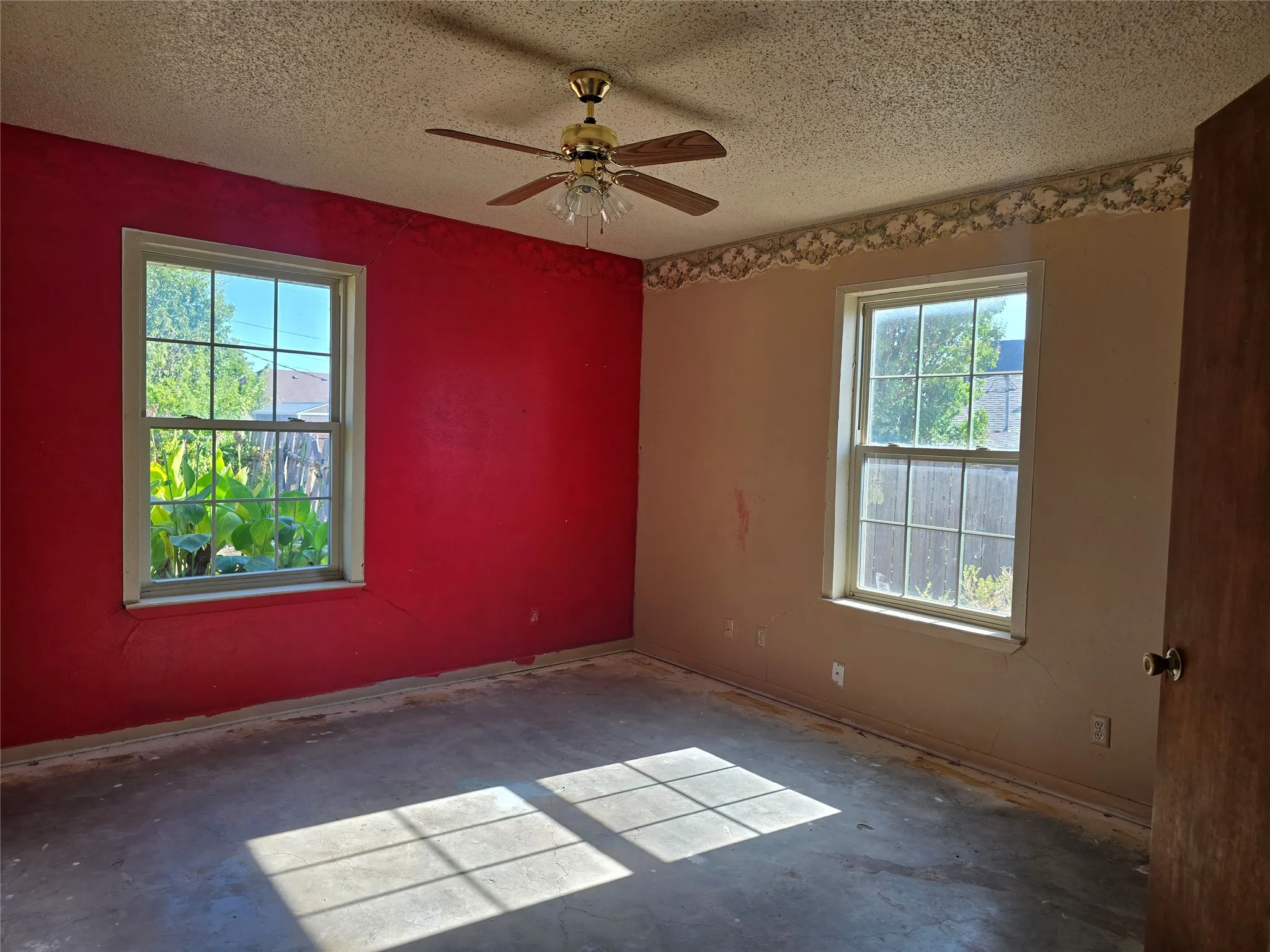 Dual windows, ceiling fan with light fixture, and textured ceiling
