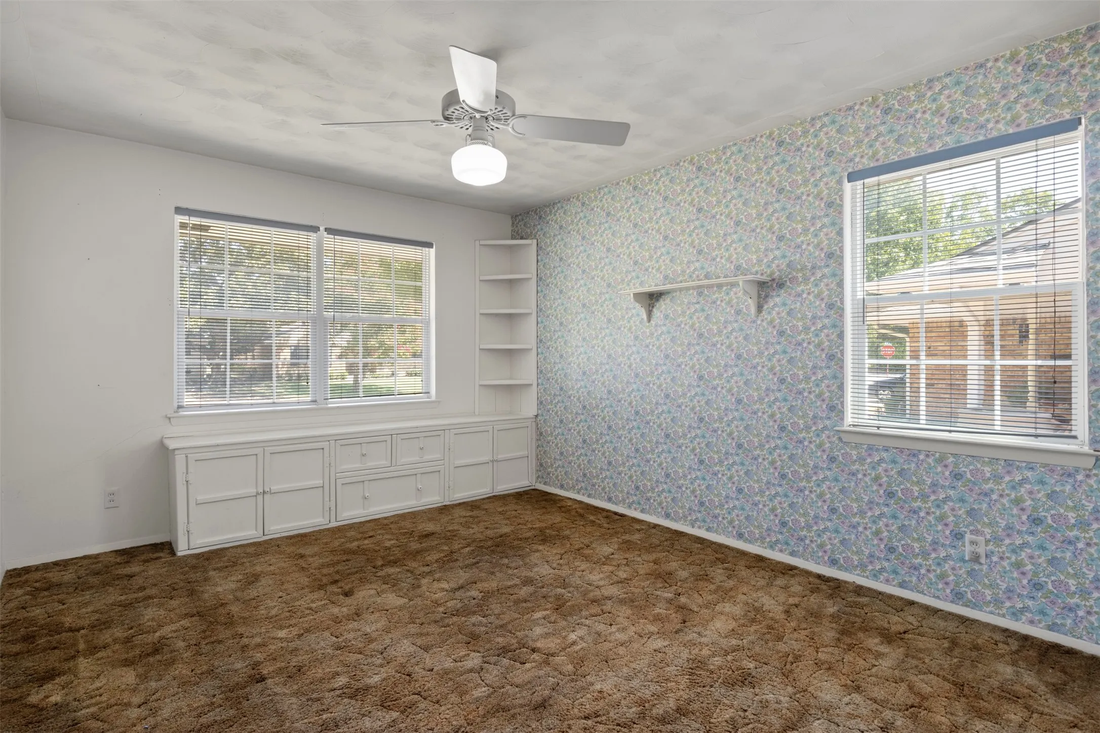 Built-in cabinetry with drawers, integrated shelving, ceiling fan with light fixture, and multiple windows